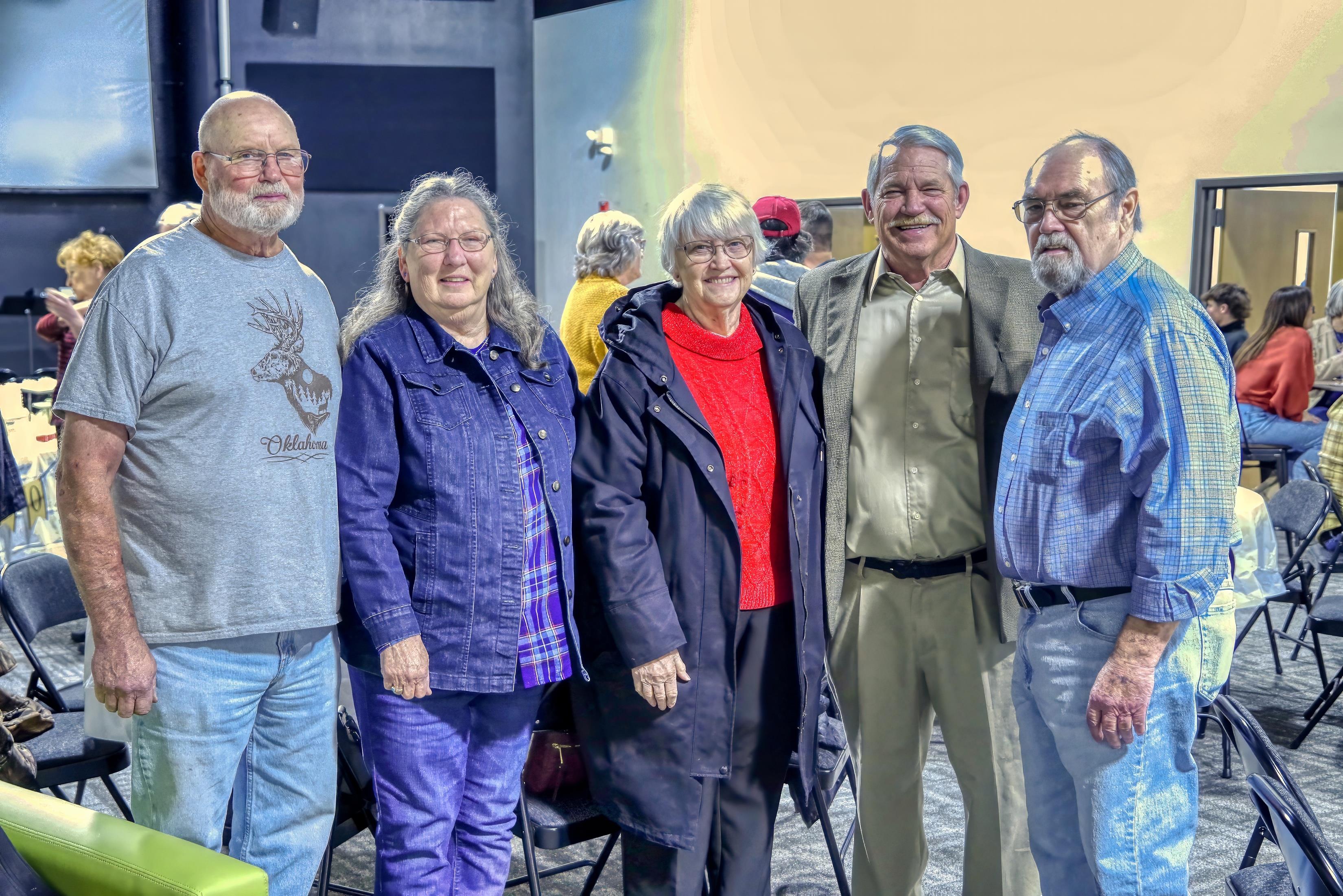 Friends celebrate their reunion at a local event, enjoying conversations and laughter together.