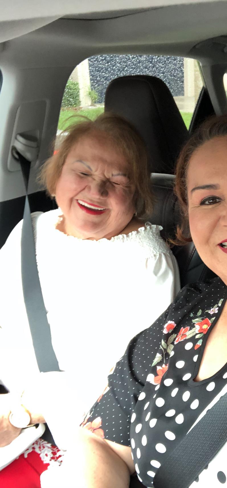 Two women sit in a car, laughing and smiling while enjoying each other's company.