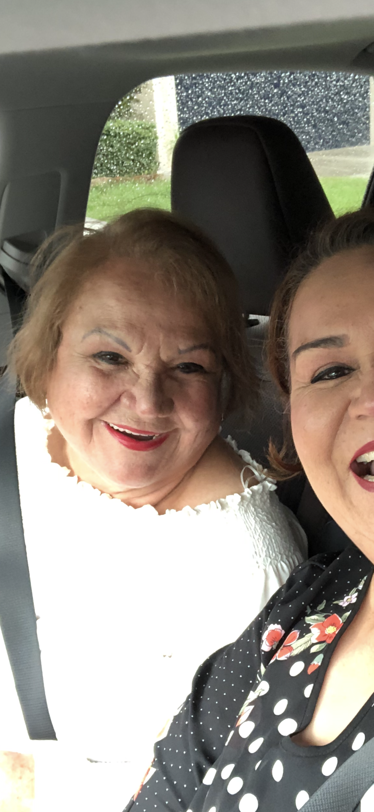 Two women enjoy a fun moment while traveling together in a car, capturing their laughter.