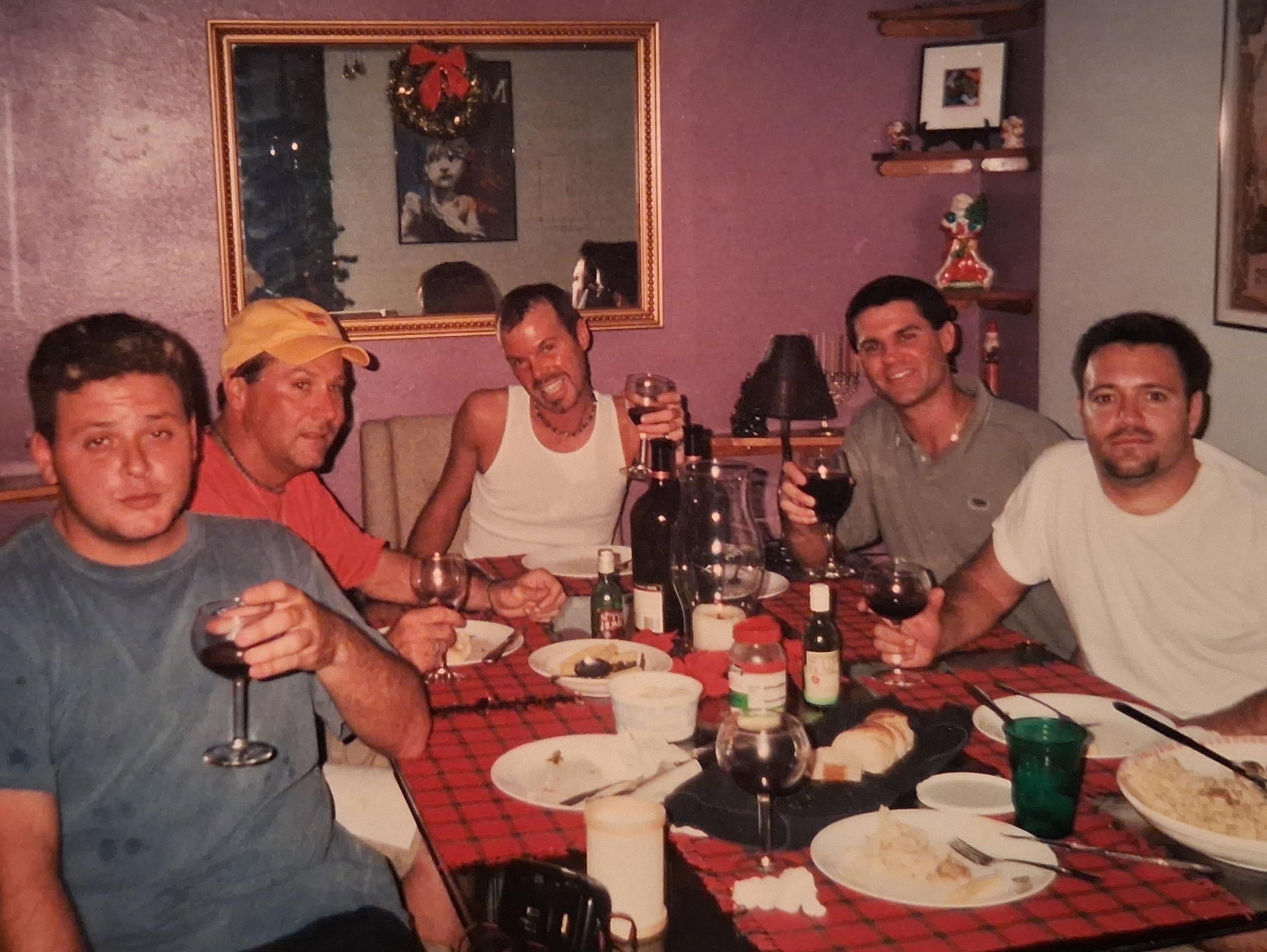Friends celebrate together at a dinner table filled with food and drinks.