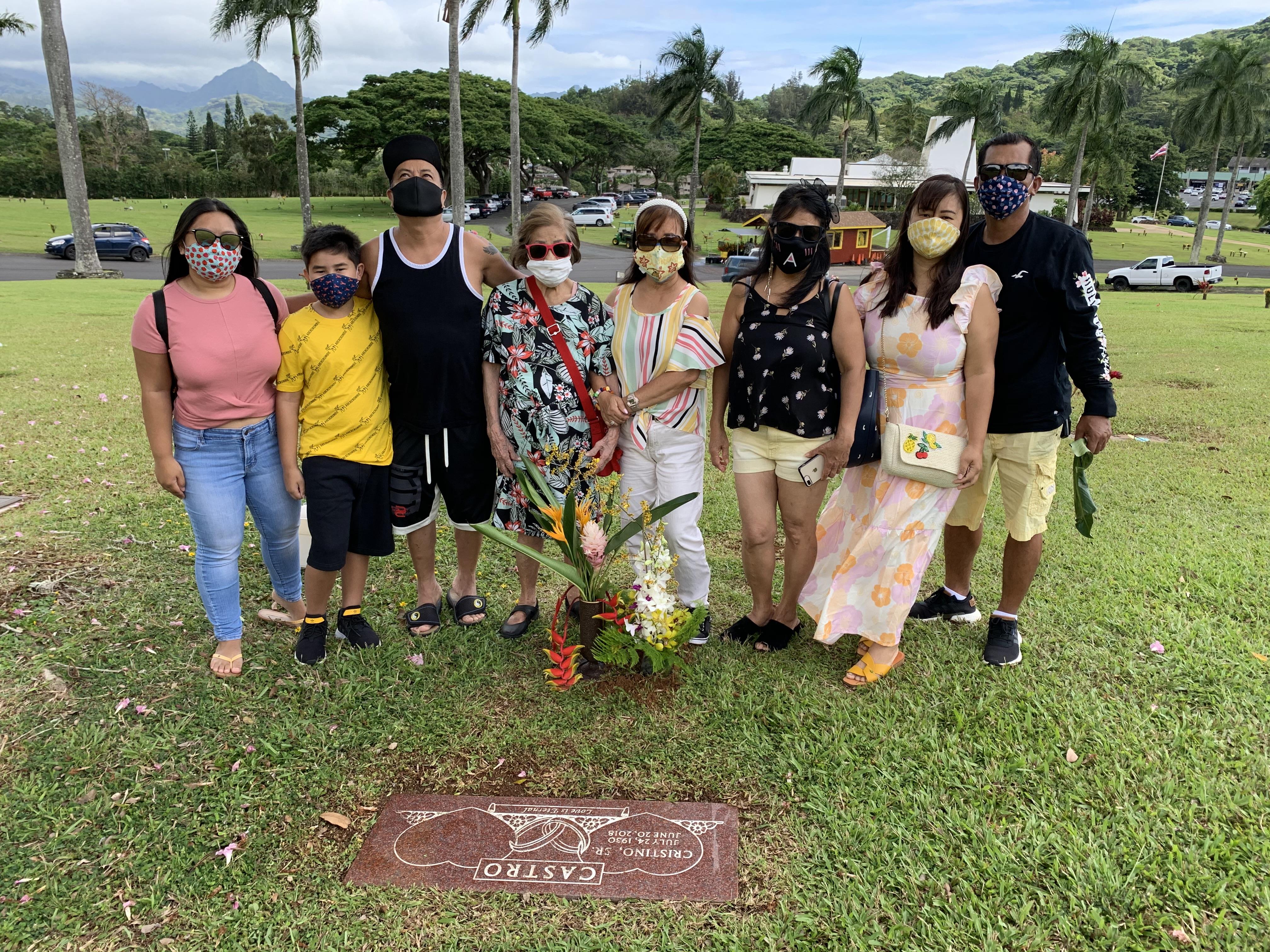 Family members gather at a gravesite, honoring life with flowers and smiles.