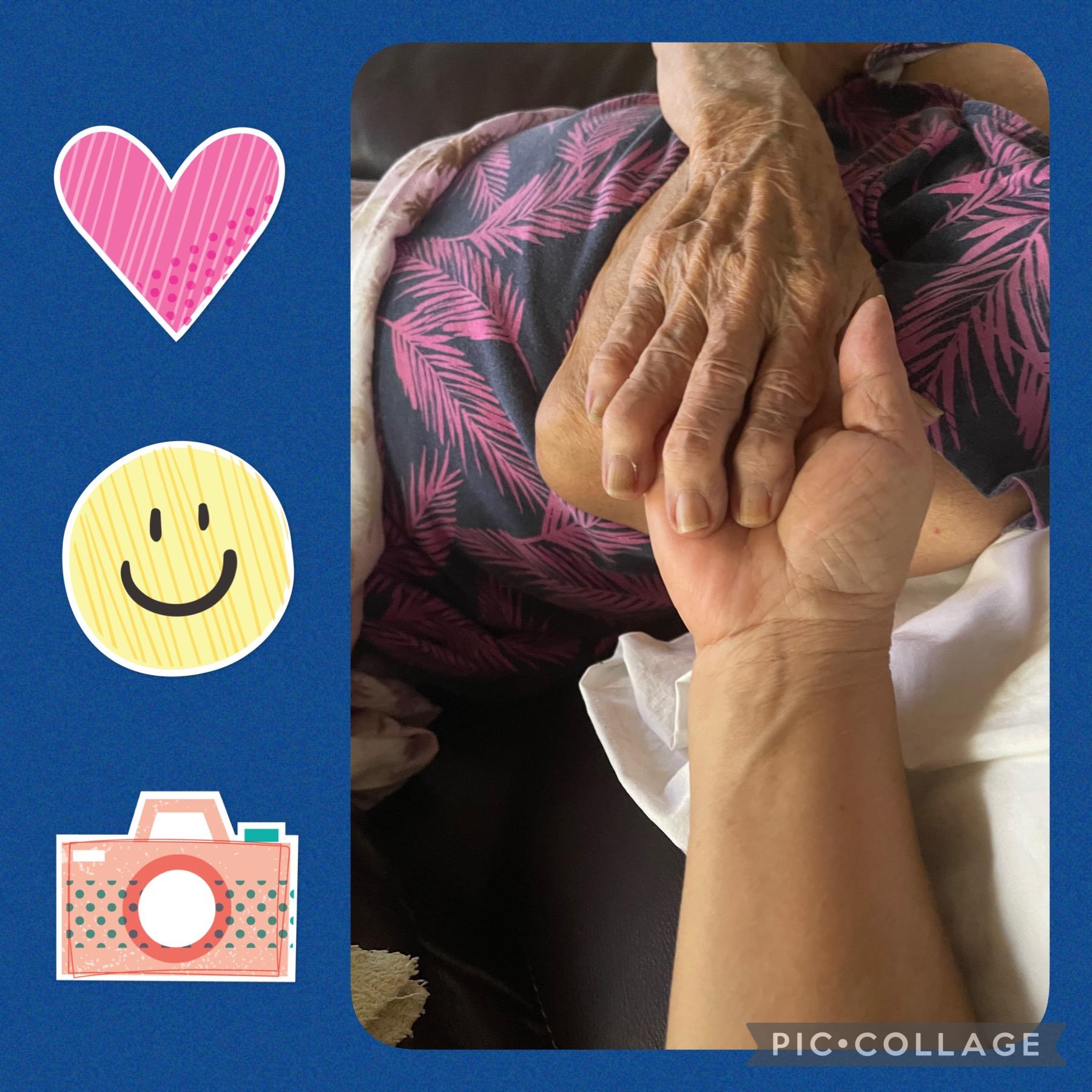 A young person holds an elderly person's hand, symbolizing care in a cozy setting.