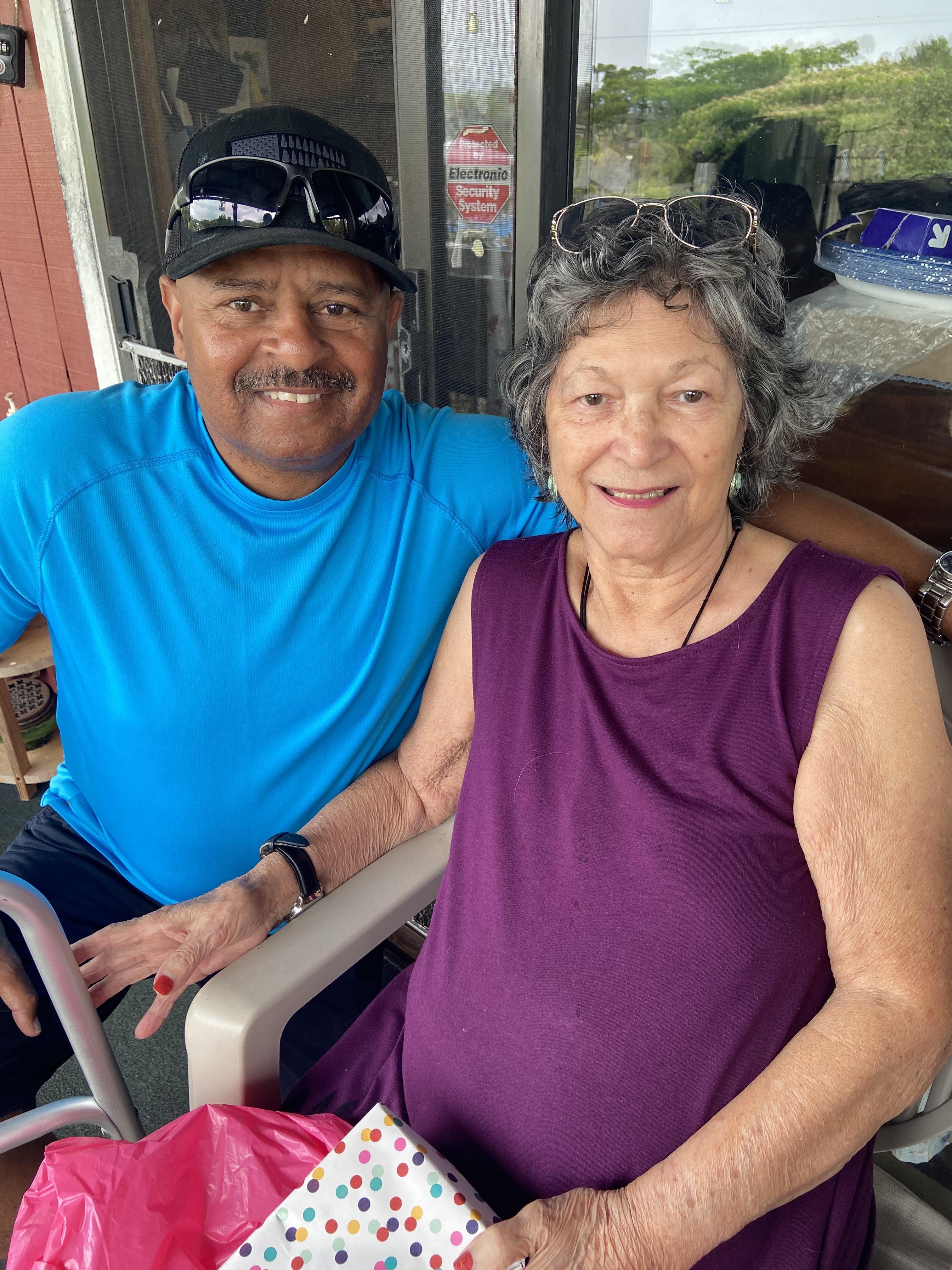 Two friends pose happily for a candid moment during a sunny day at a relaxed outdoor location.