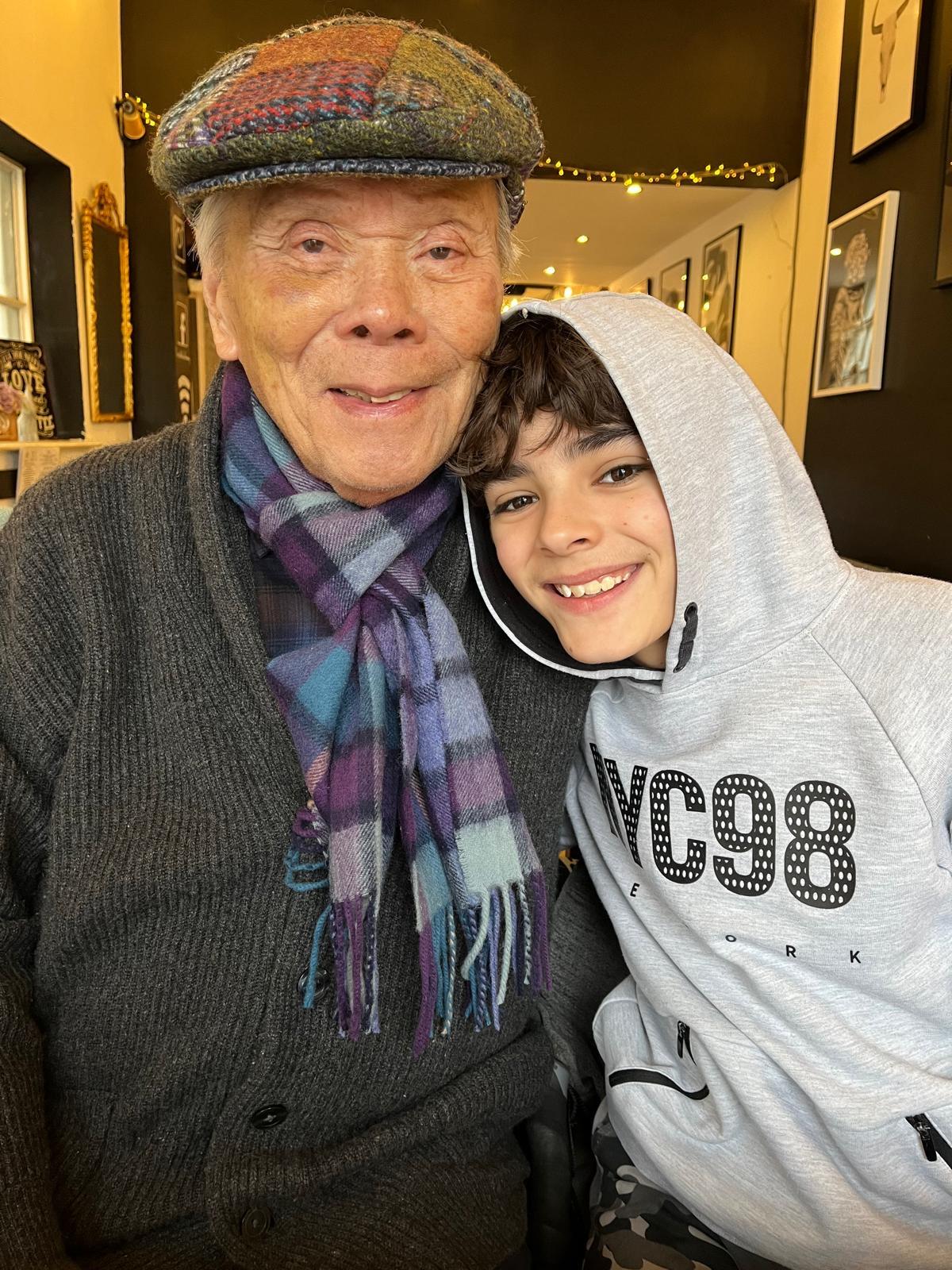 Grandfather and grandson enjoying quality time together in a warm cafe, laughing and smiling.
