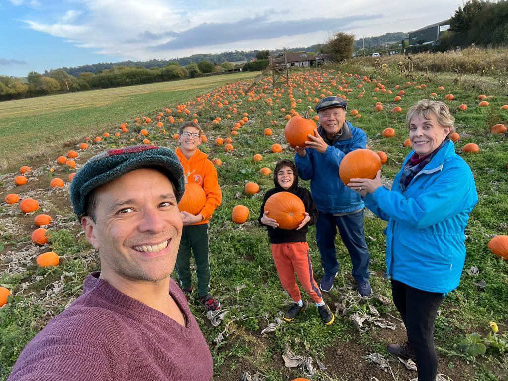Family members happily picking pumpkins in a vibrant autumn field.