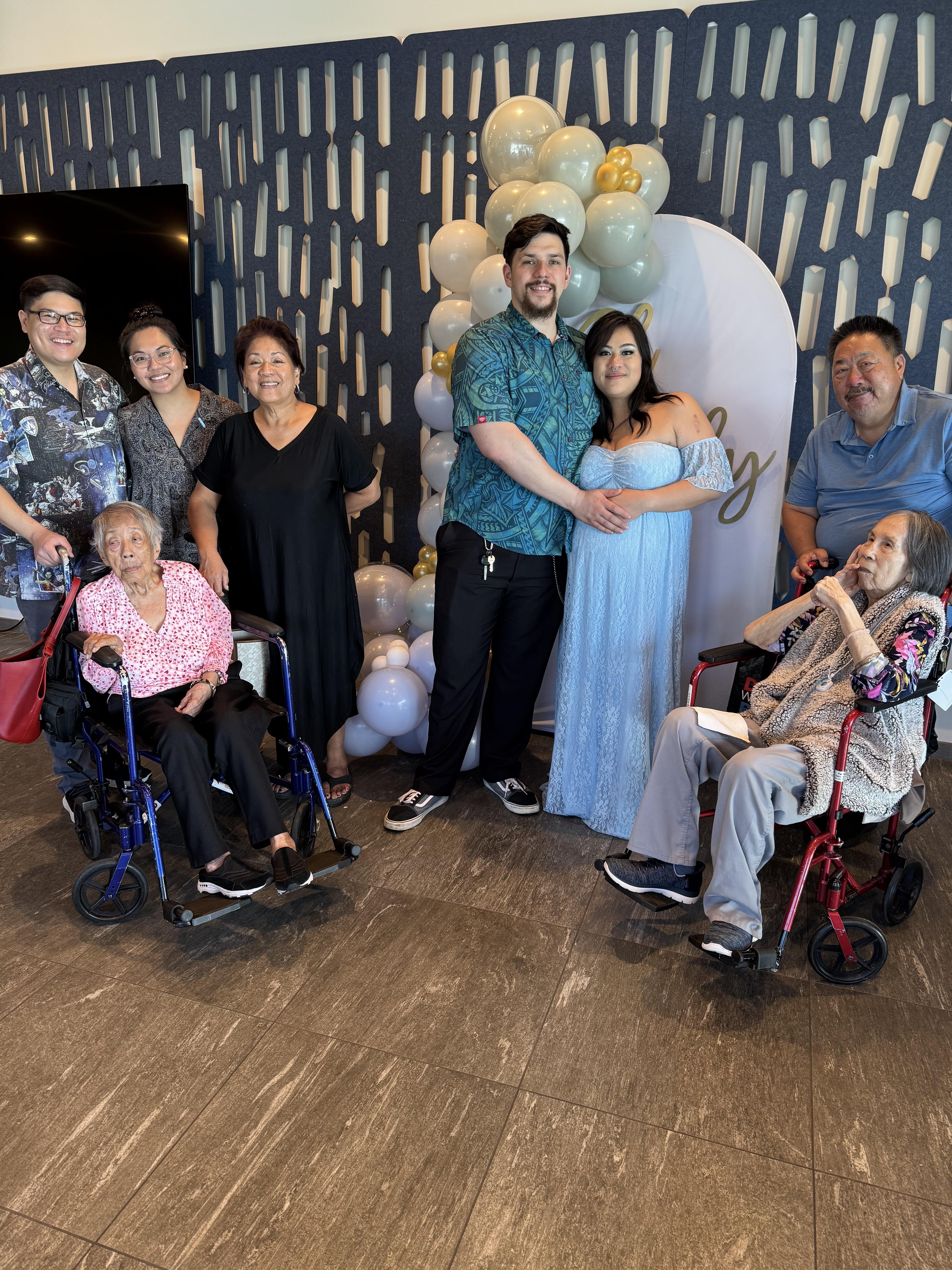 Family members gather together, celebrating a milestone with decorations and joyful expressions.