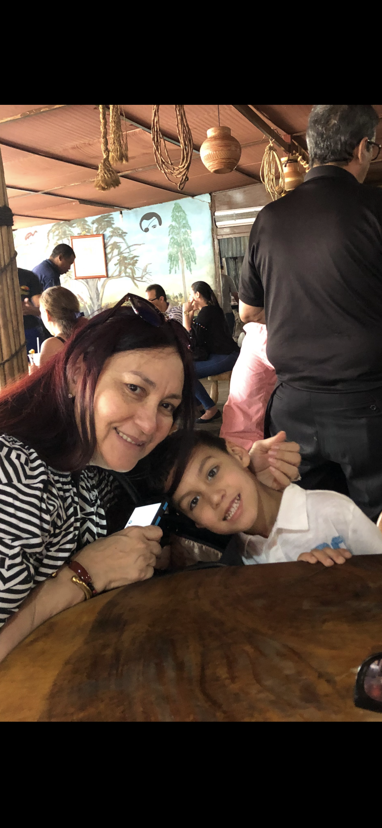 A woman and a young boy share a happy moment in a lively restaurant filled with diners.