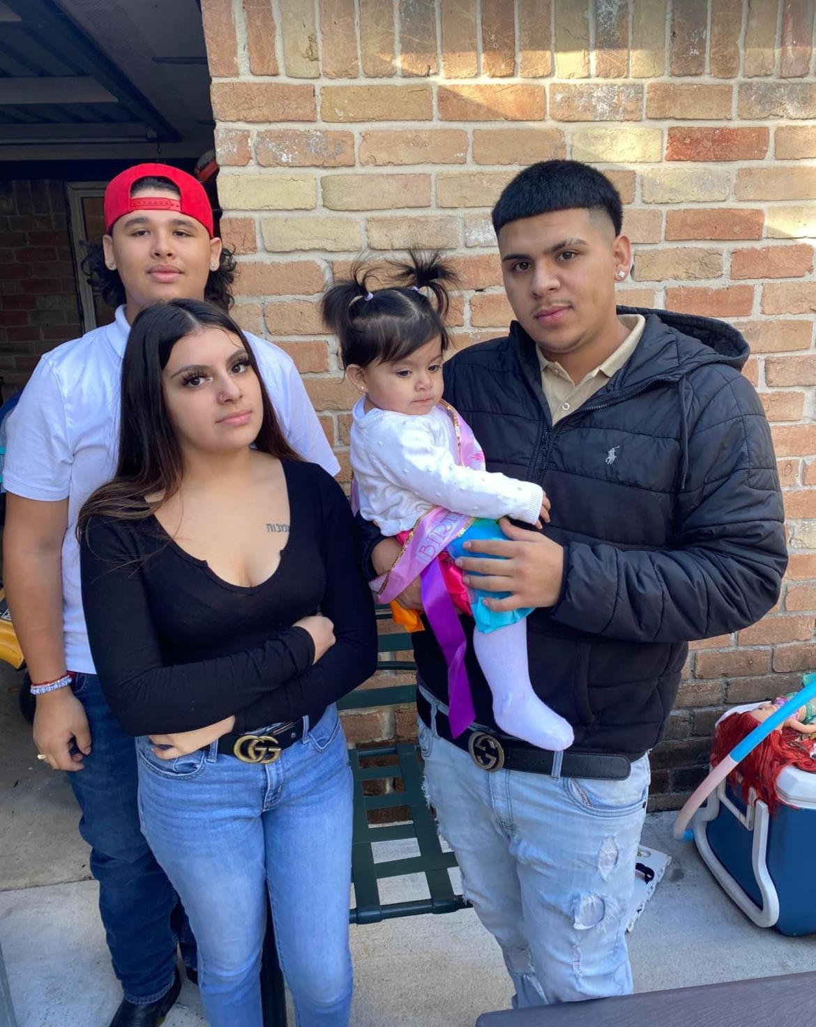 Four family members enjoy a relaxed moment outdoors, with one adult holding a young girl.