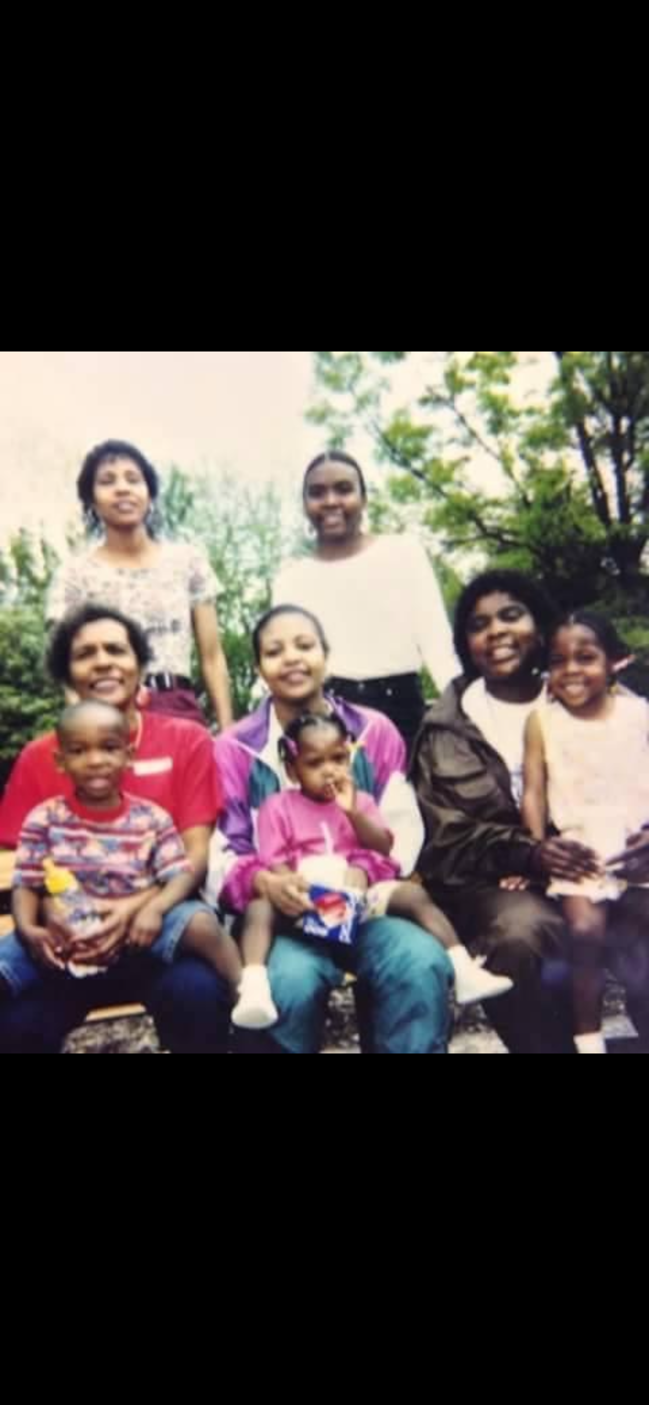 A joyful family gathering takes place in a lush park as relatives share moments together.