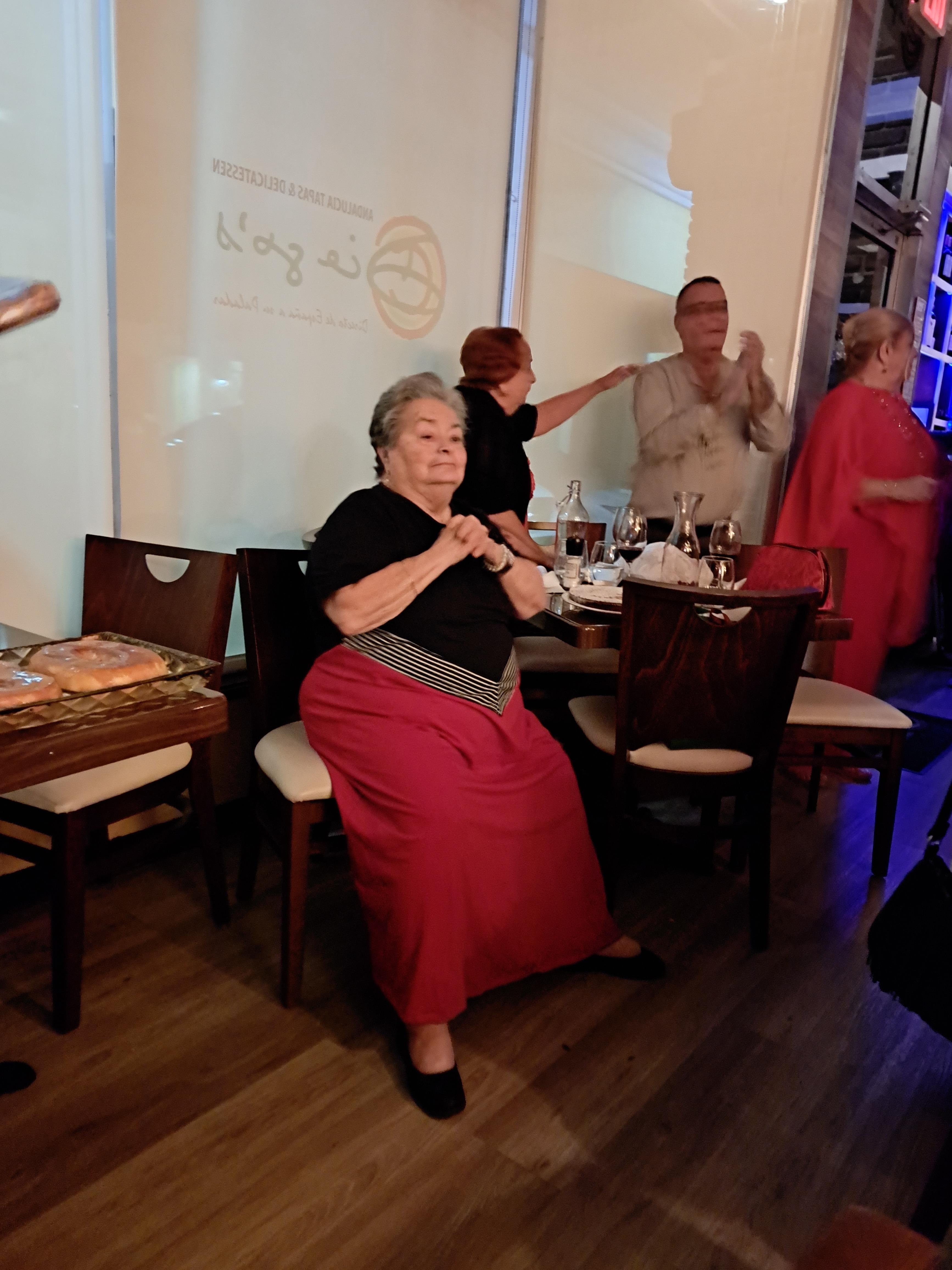 Guests laugh and dance while seated and standing in a vibrant restaurant ambiance.