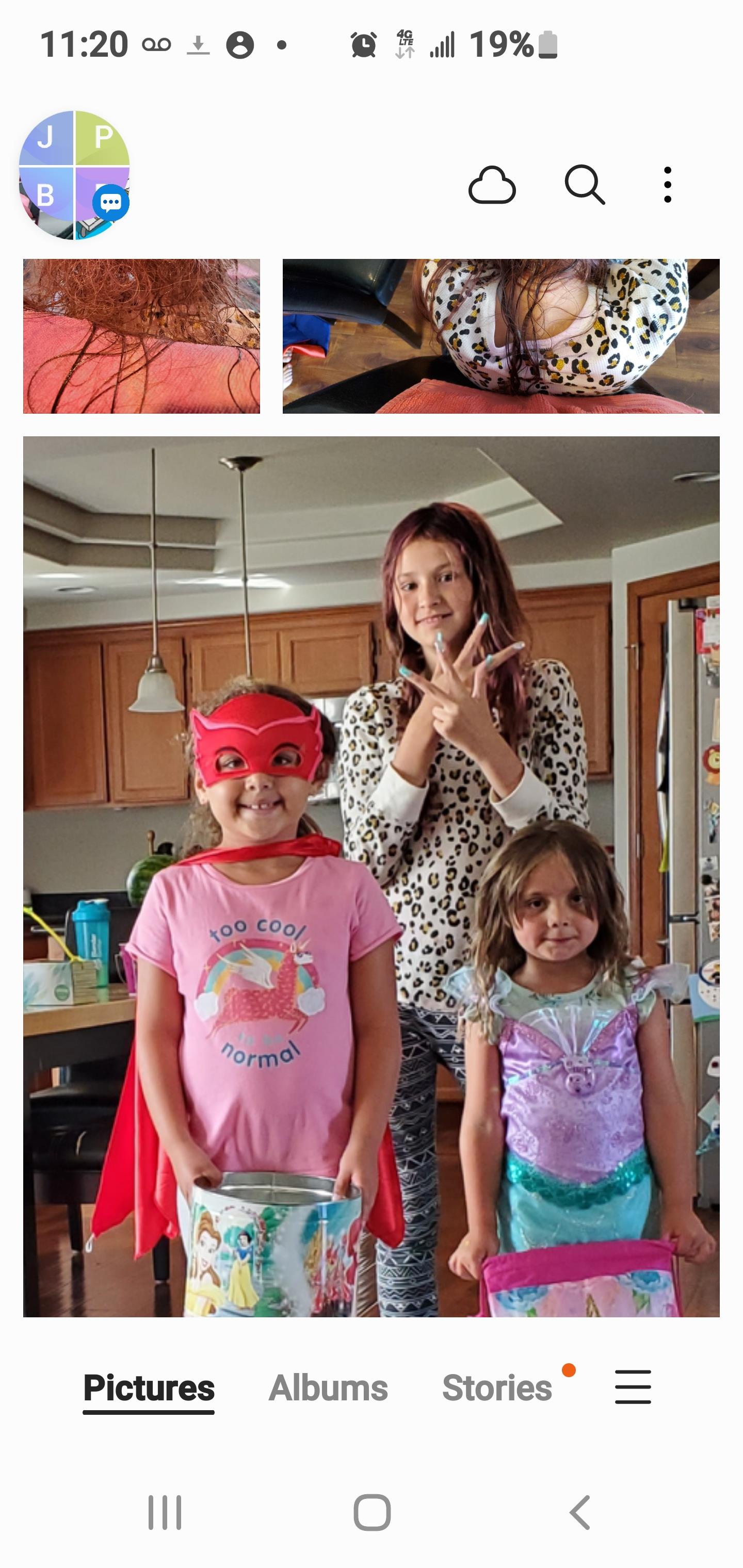 Three children dressed in superhero costumes are having a playful moment in a kitchen.