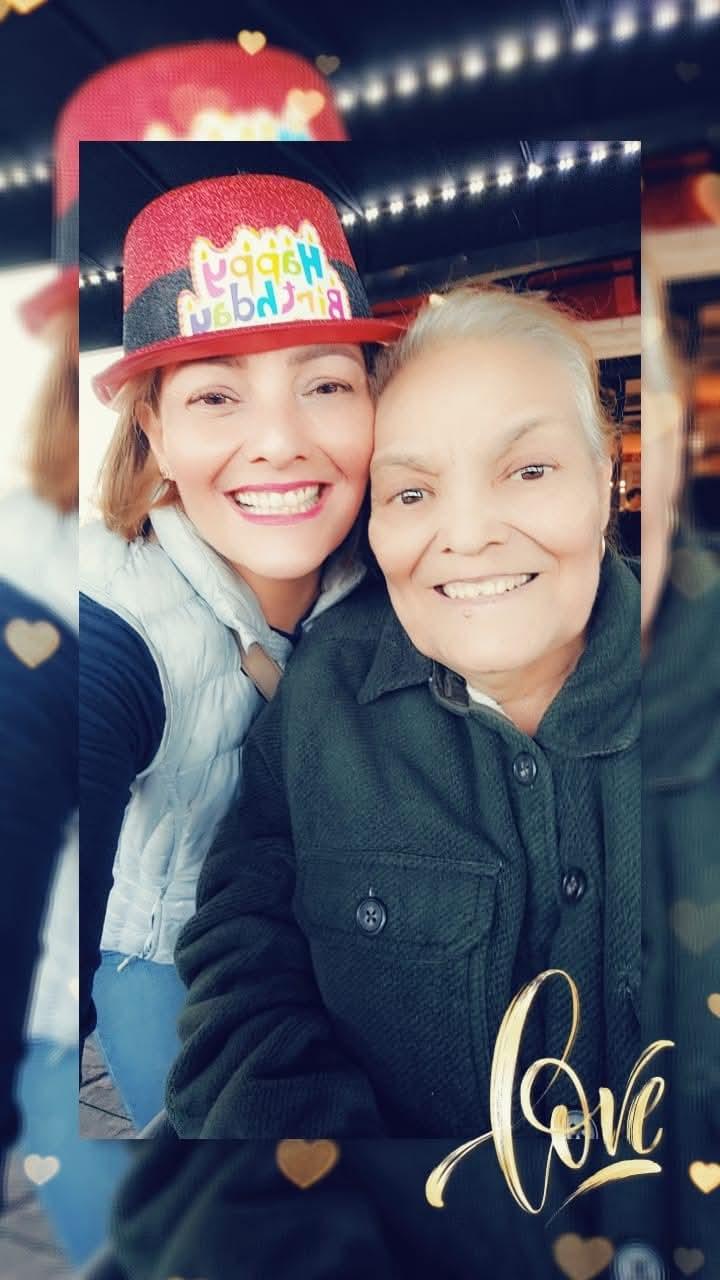 Two women smile warmly while celebrating a birthday at a cheerful cafe in the afternoon.