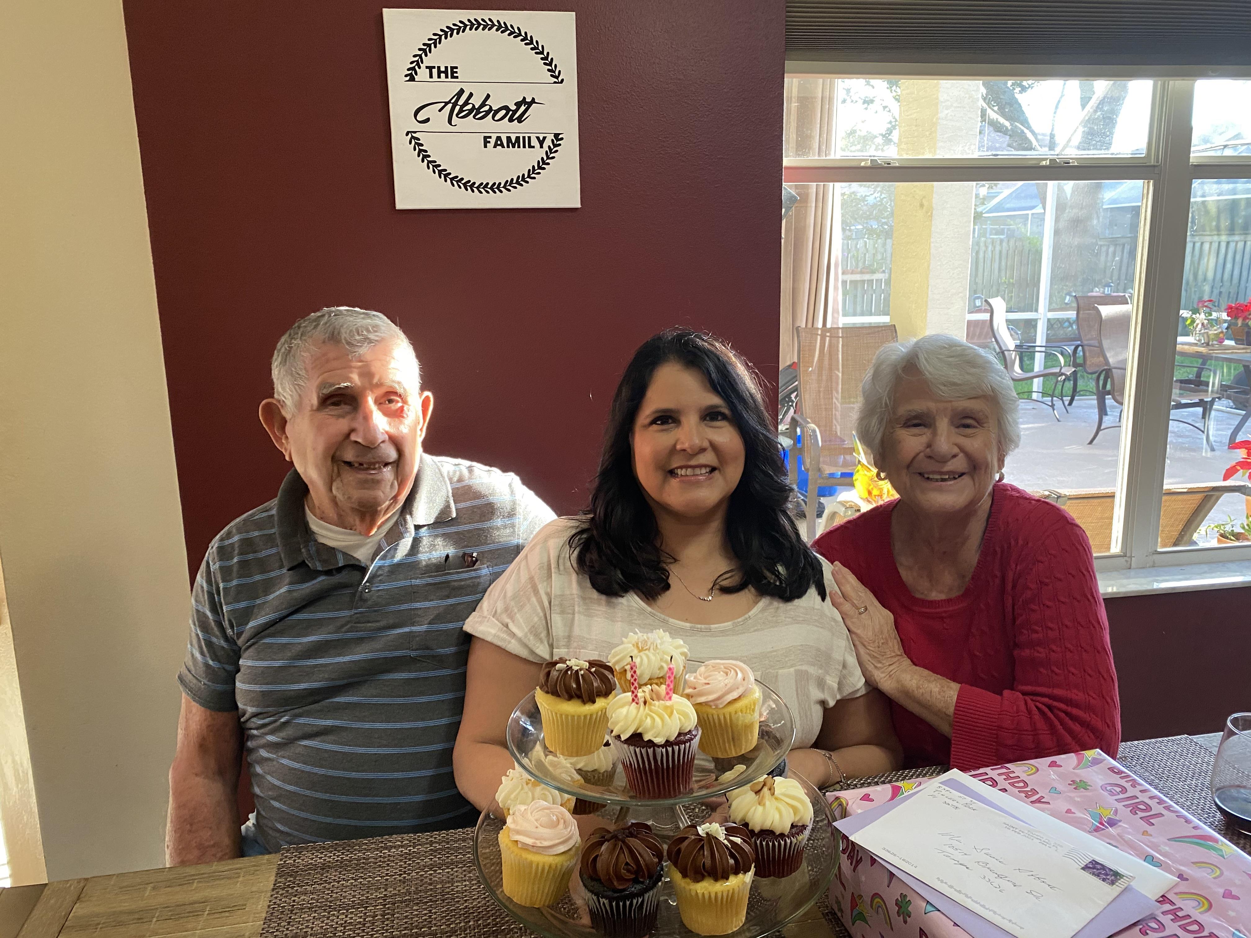 Three family members enjoy a delightful gathering with cupcakes in a cozy home atmosphere.