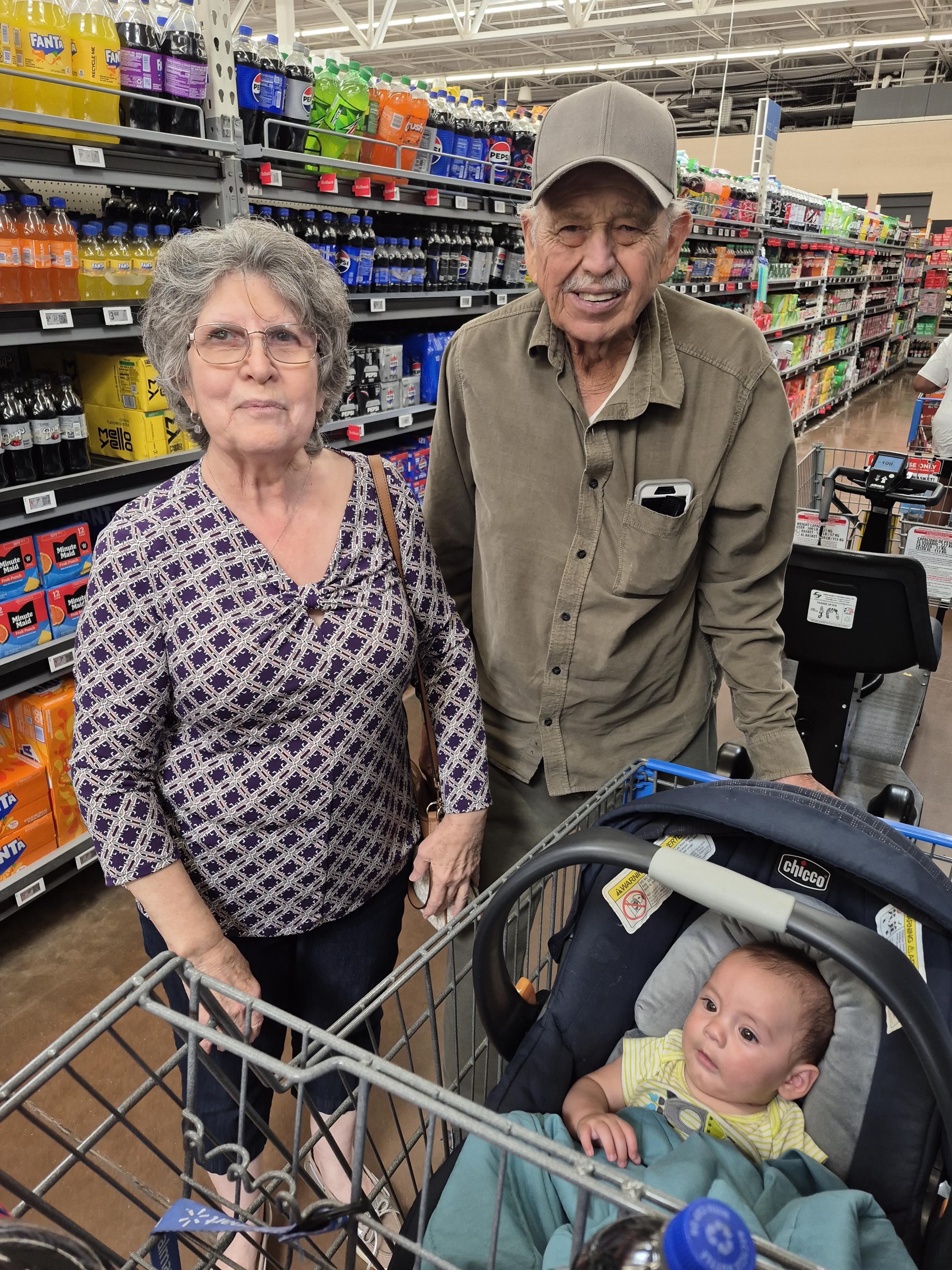 Couple enjoys shopping together with their grandchild in baby cart during the afternoon.