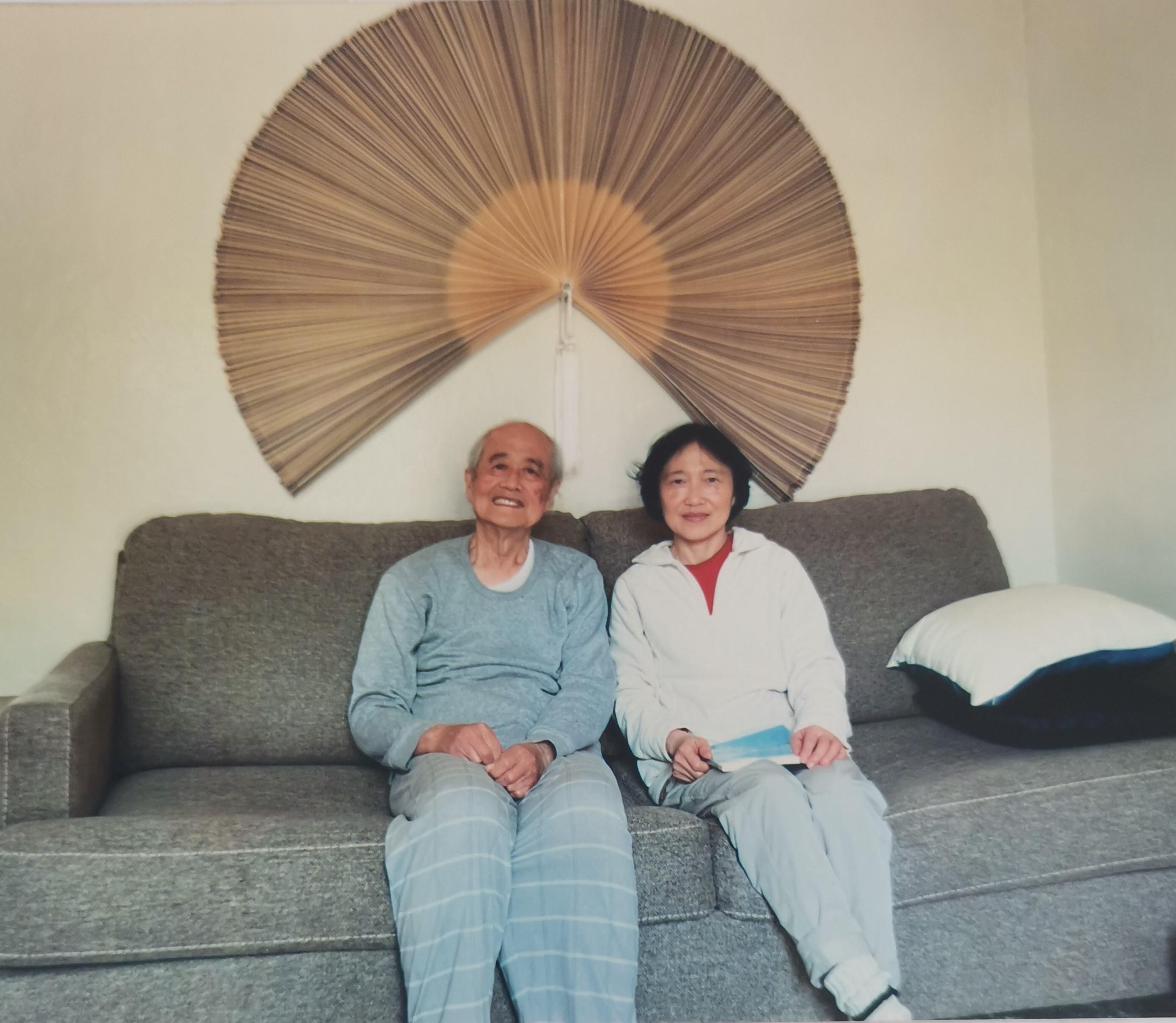 Two happy individuals sit together on a plush sofa in a relaxed home setting filled with warm decor.