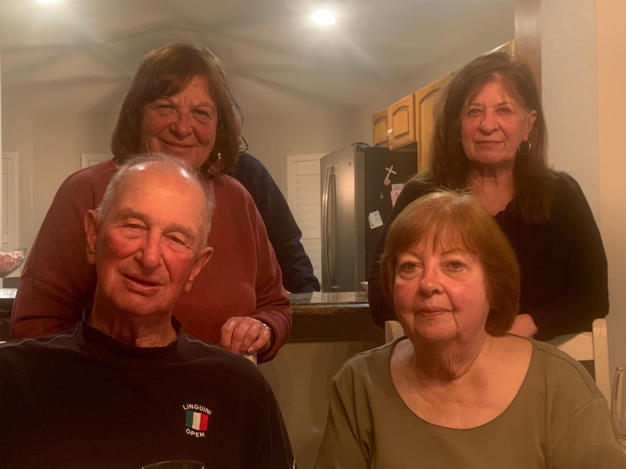 Four family members gather around sharing smiles and stories in a warm kitchen ambiance.