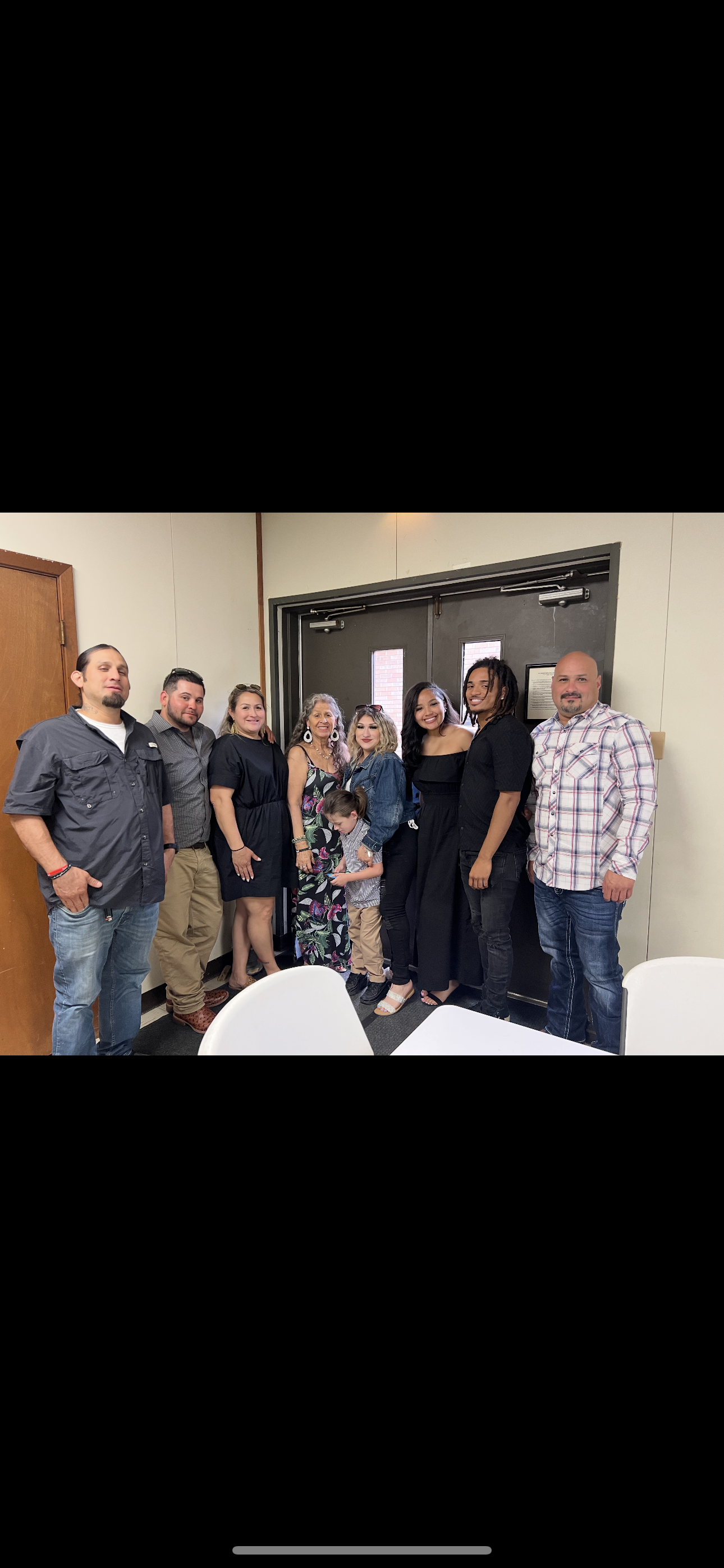 Eight people gather by a door, smiling and enjoying a celebration together.