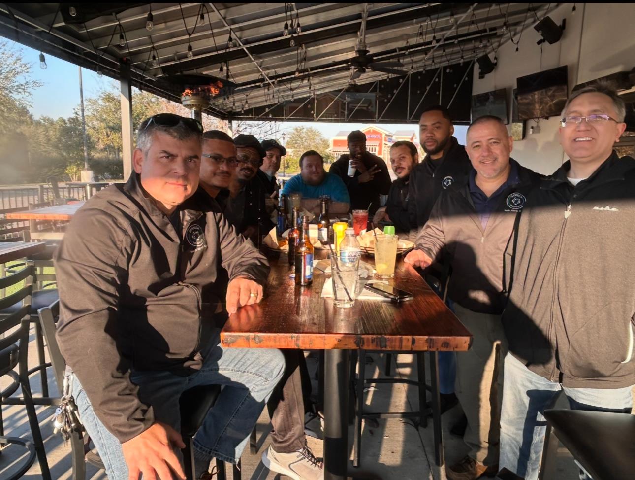 Friends gather at a bar, sharing laughter and drinks under warm evening light.