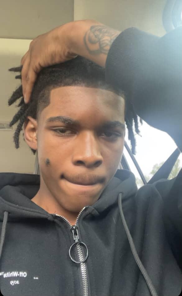 A man with dreadlocks and a hand on his head