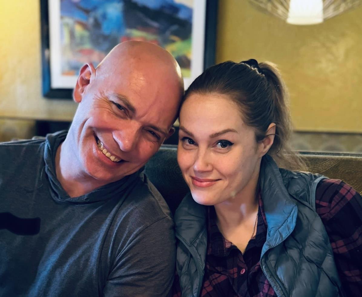 A couple smiles happily in a cozy cafe, enjoying their time together.