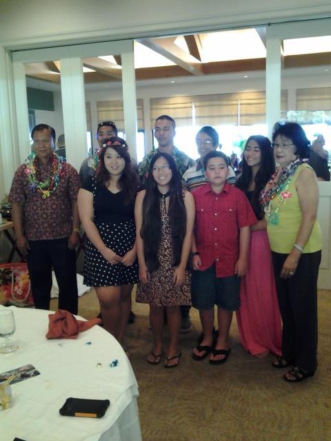 Smiling family in festive attire gathered at a restaurant celebrating together.