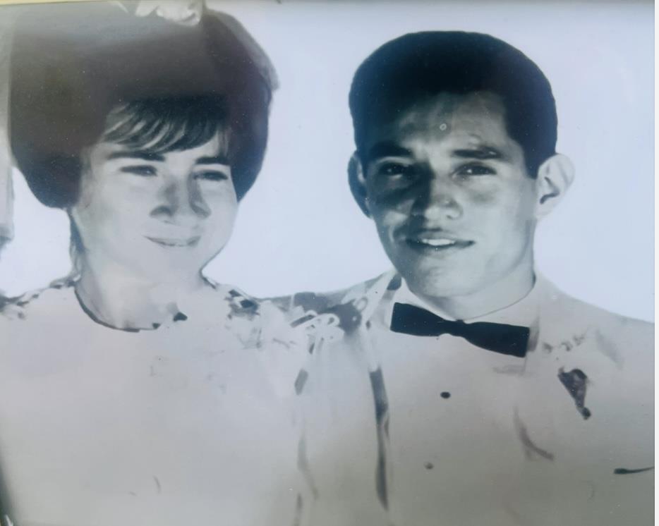 Couple in formal attire smiles together during their wedding in a joyful atmosphere outdoors.