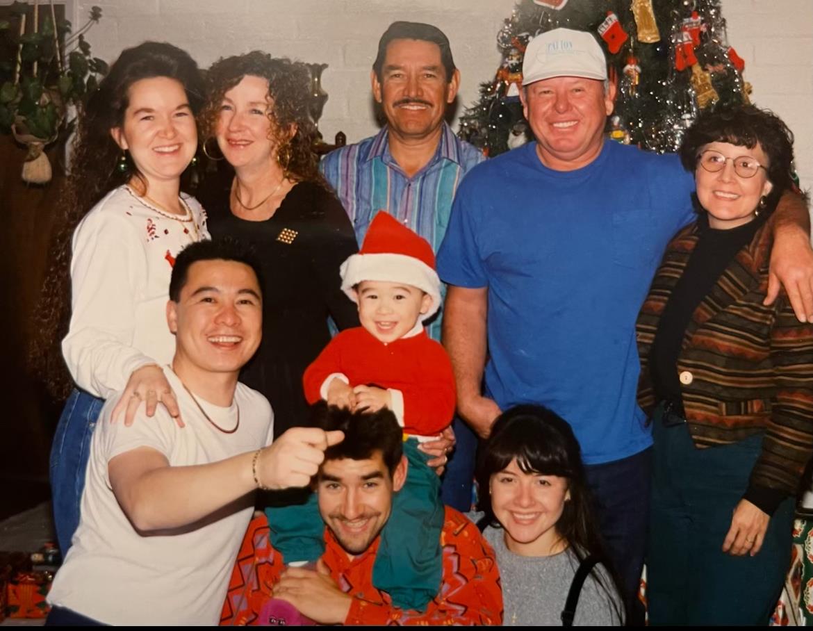 Group of family members celebrating a holiday, showcasing happiness and a decorated tree.