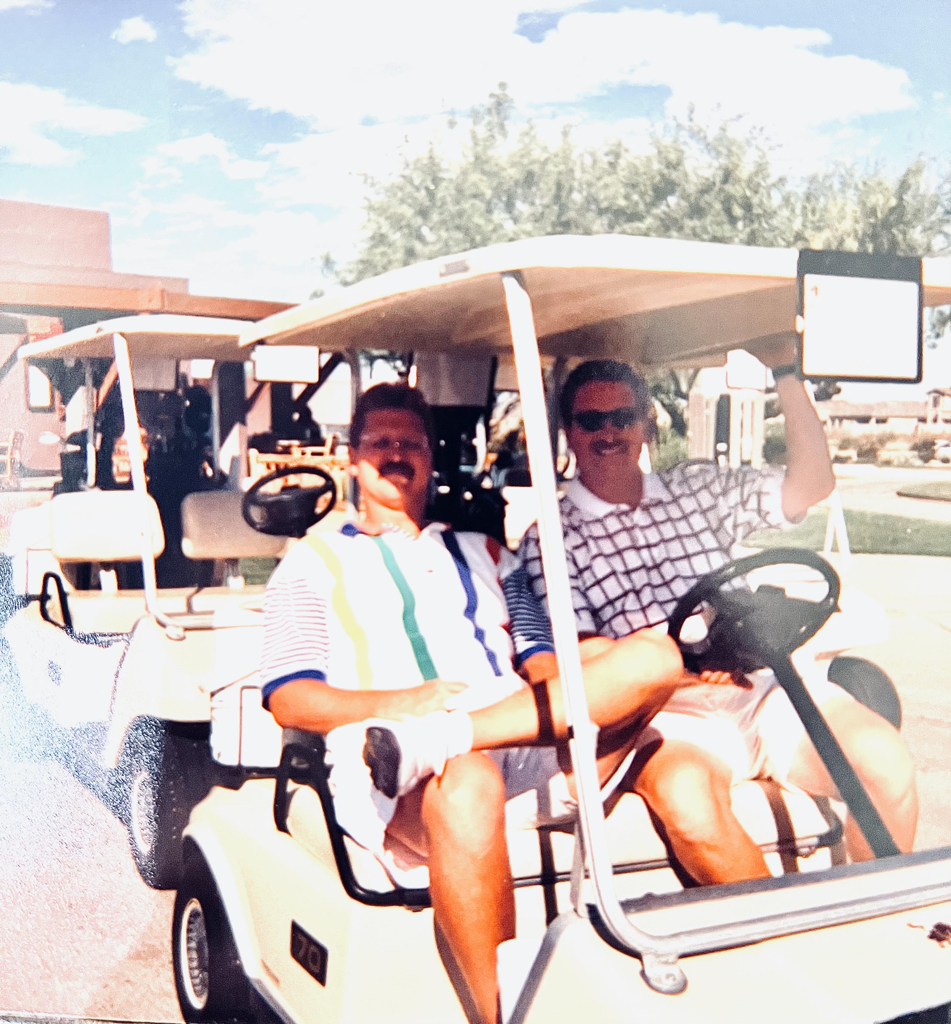 Two friends ride in a golf cart, smiling and enjoying their time on a sunny day at the course.