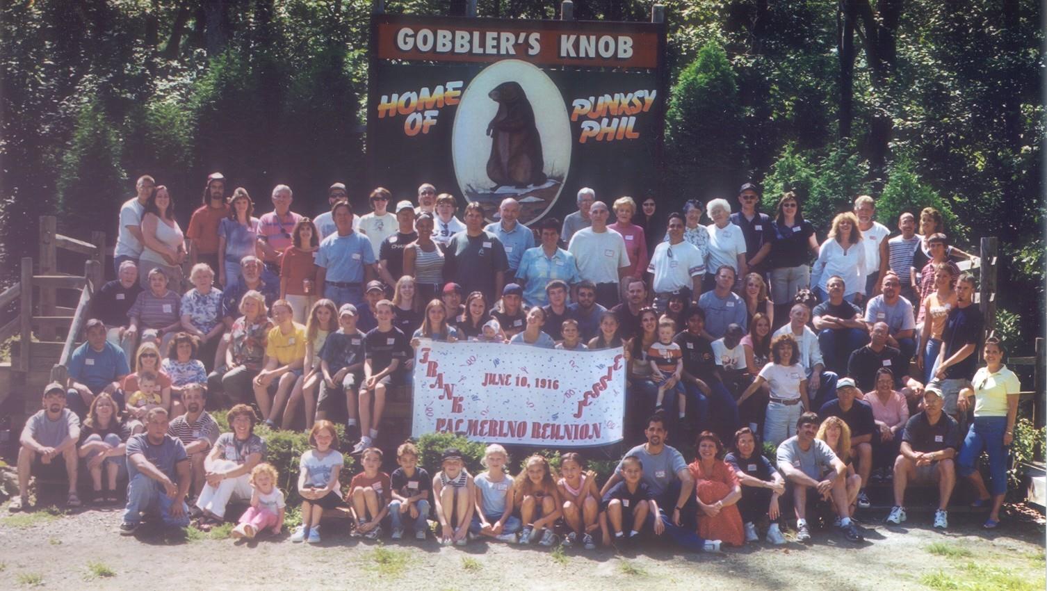 Large group poses together at Gobbler's Knob holding a banner celebrating their beloved groundhog.