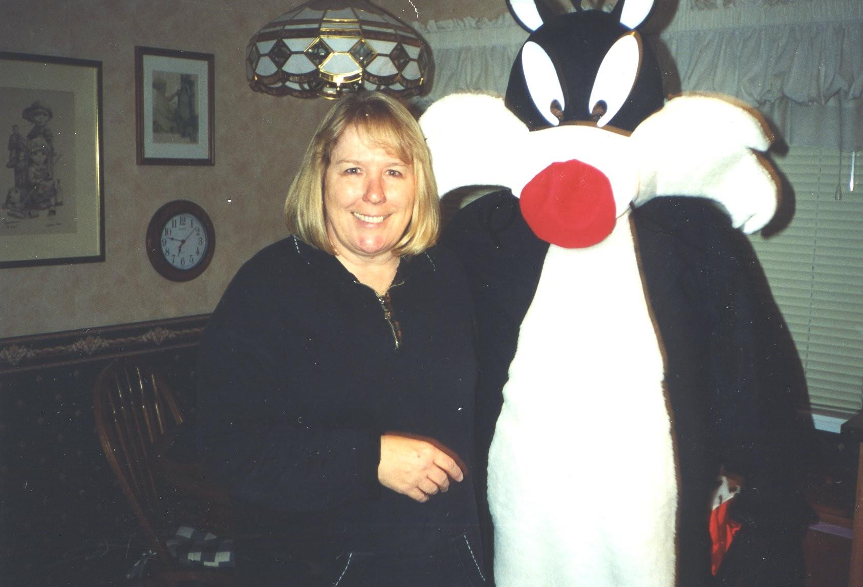 A woman hugs a cartoon character in a cozy, decorated indoor setting.