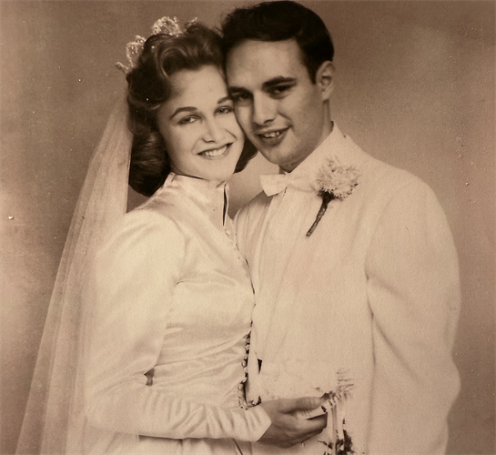 A joyful couple poses for a wedding portrait, dressed elegantly, radiating love and happiness.