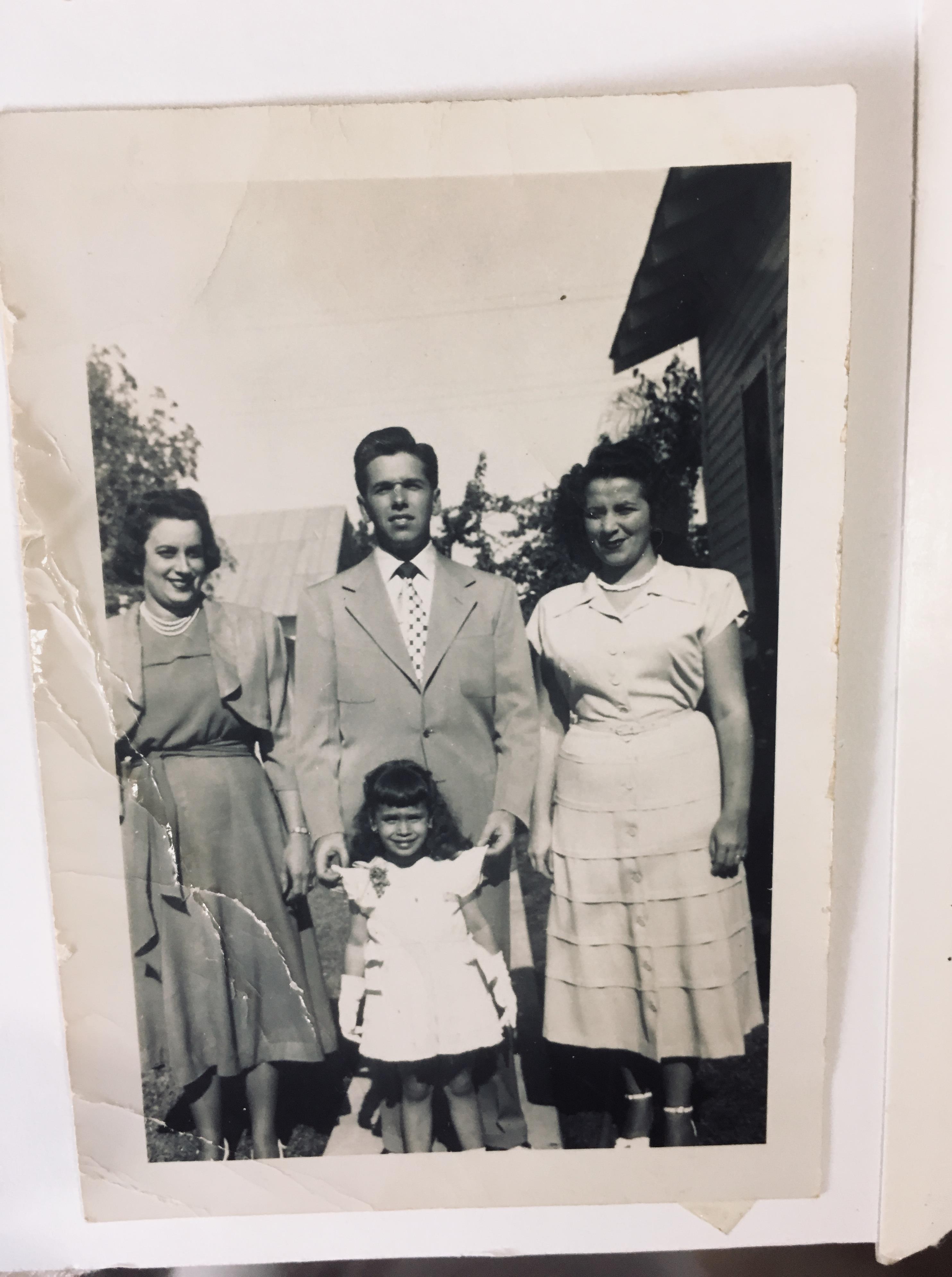Four people stand together outdoors, smiling warmly.