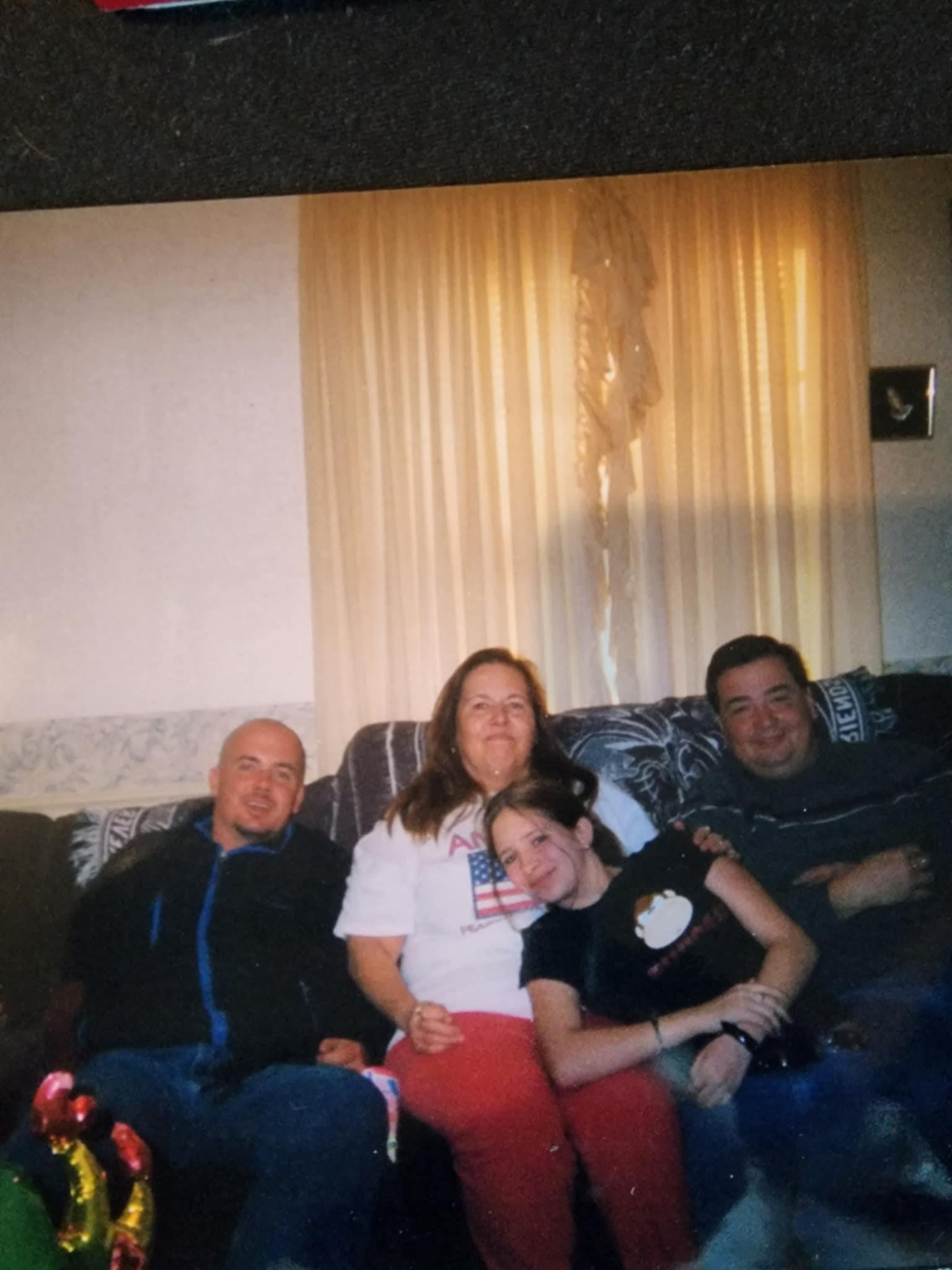 Four friends sit close together on a couch, smiling and sharing good times in a warm living room.