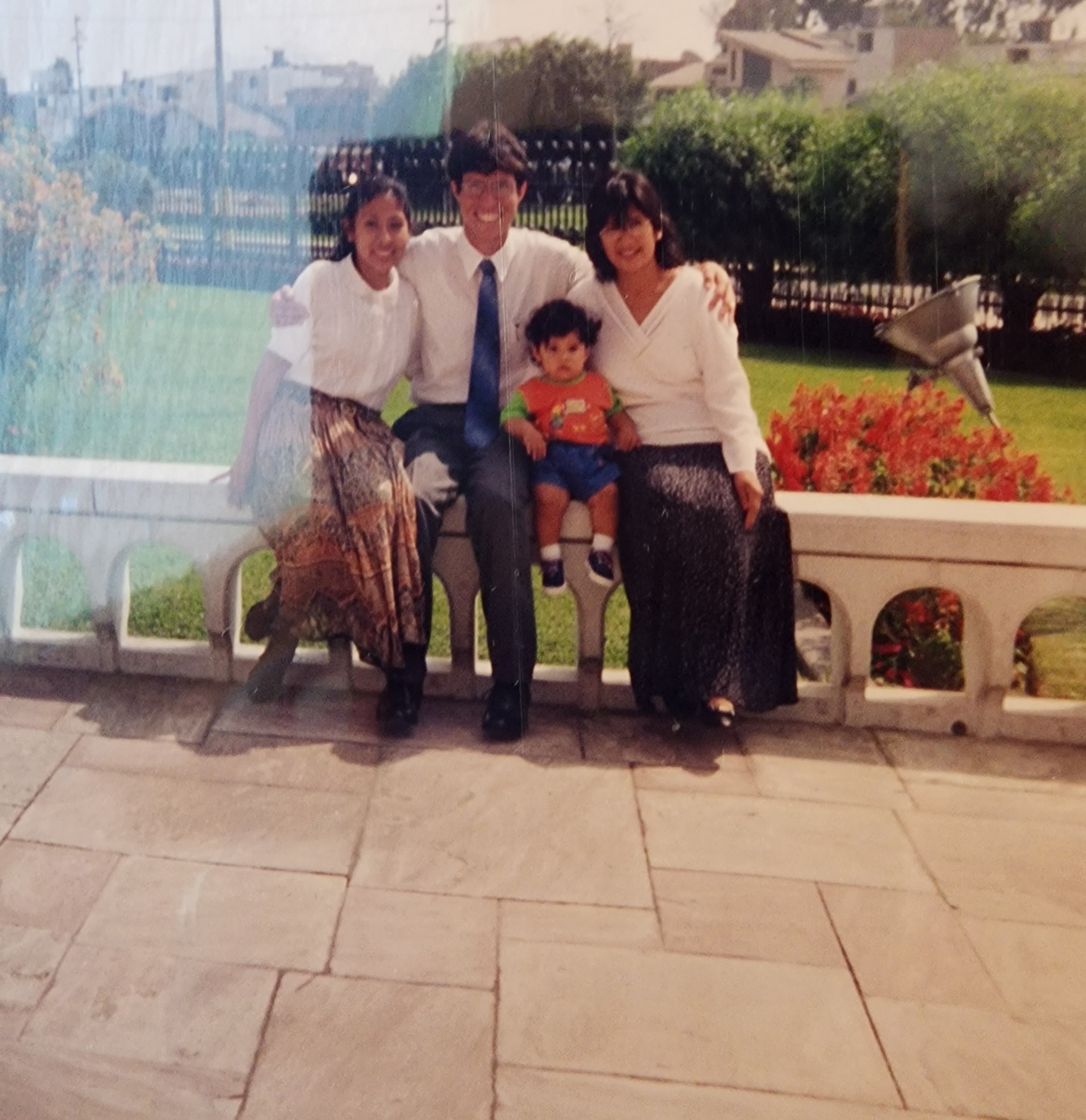 Four family members are enjoying time together in a lush garden filled with vibrant flowers.