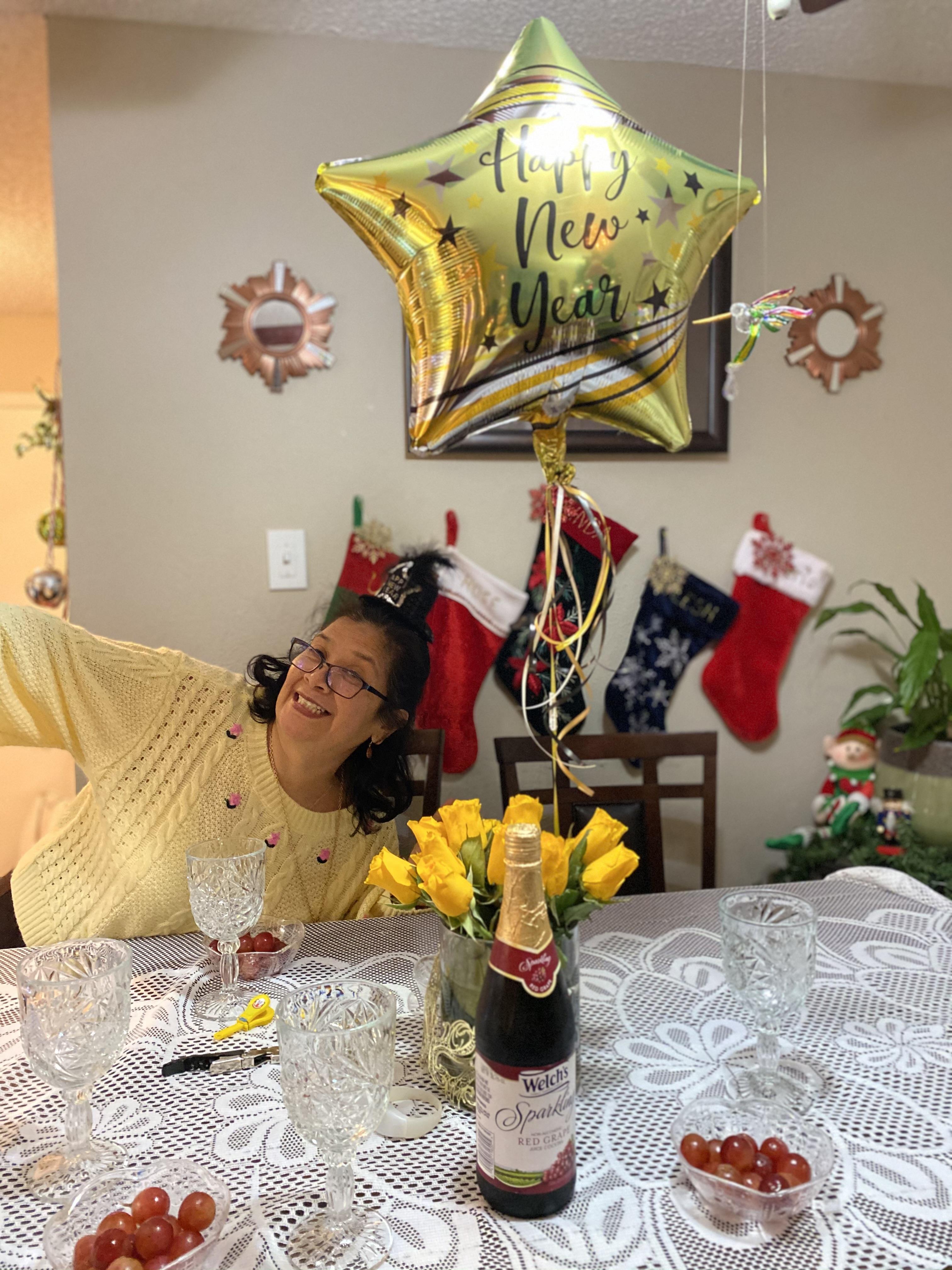 Woman smiles and takes a selfie at a New Year celebration with decorations and flowers.