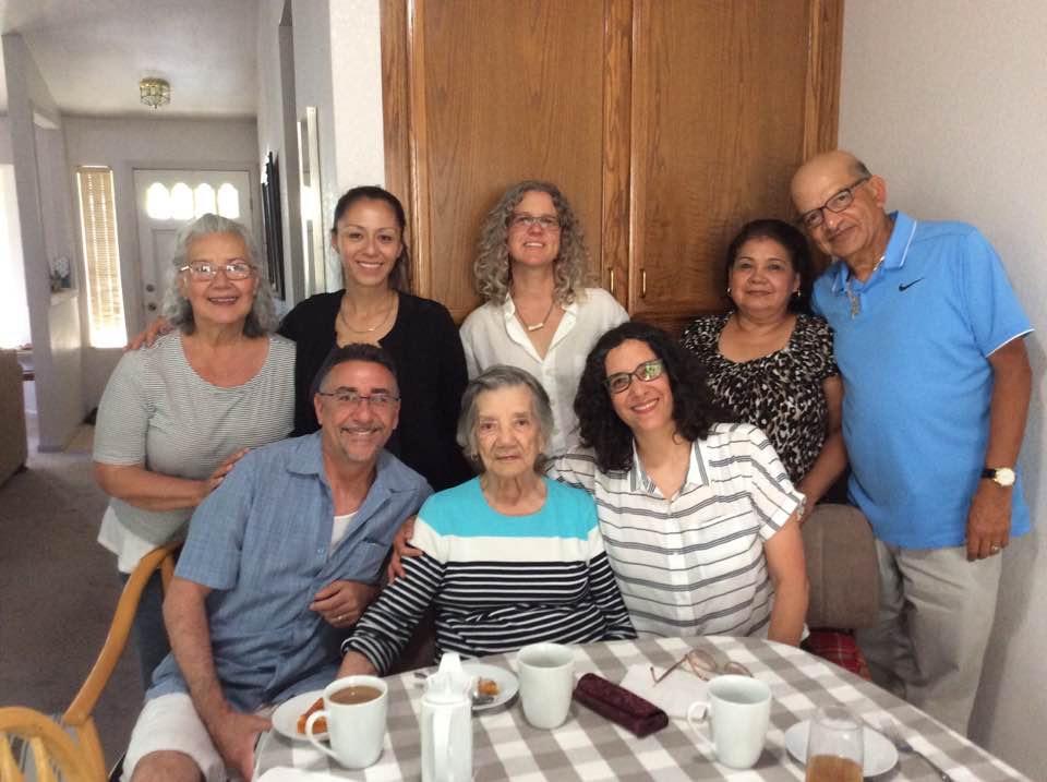 Eight family members enjoy a cheerful reunion in a bright kitchen, sharing smiles and laughter.
