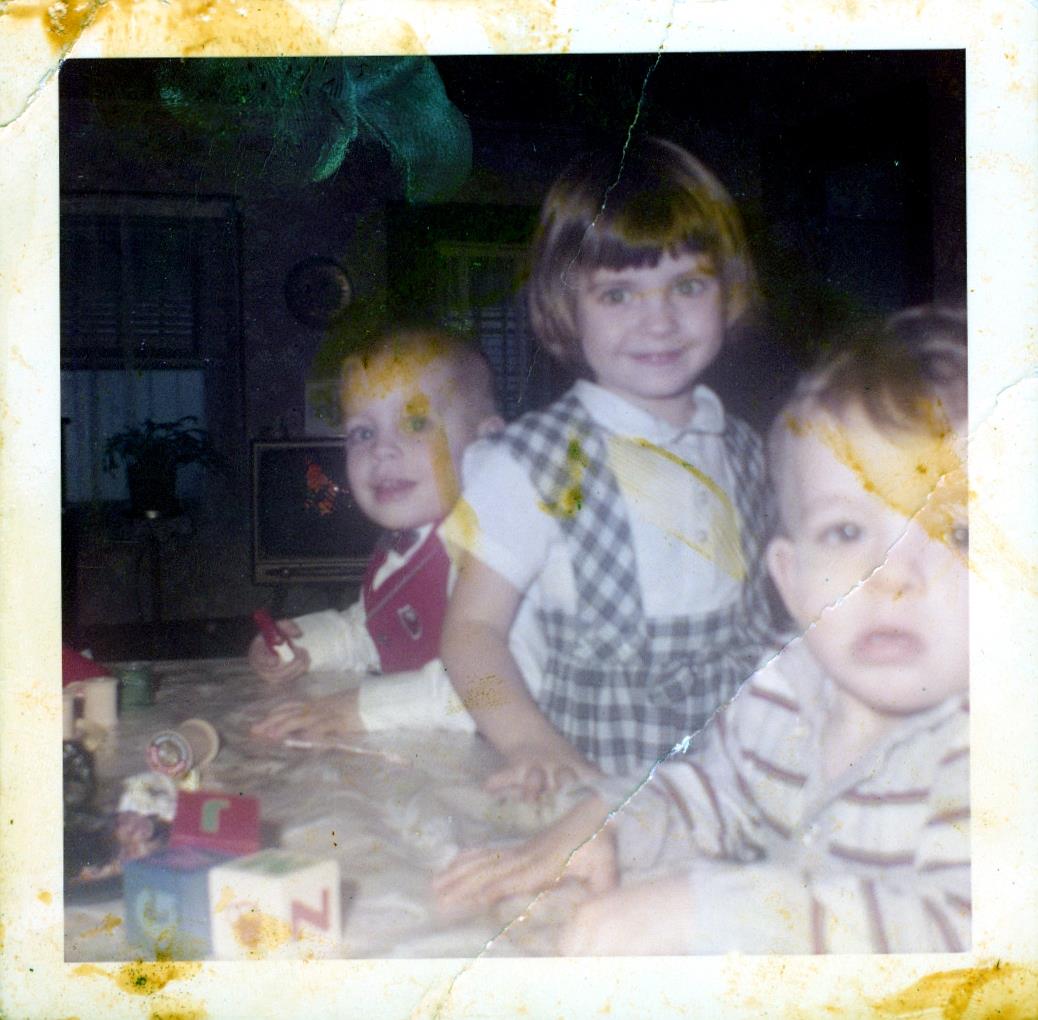 Three kids happily play with toys at a family gathering in a cozy setting.