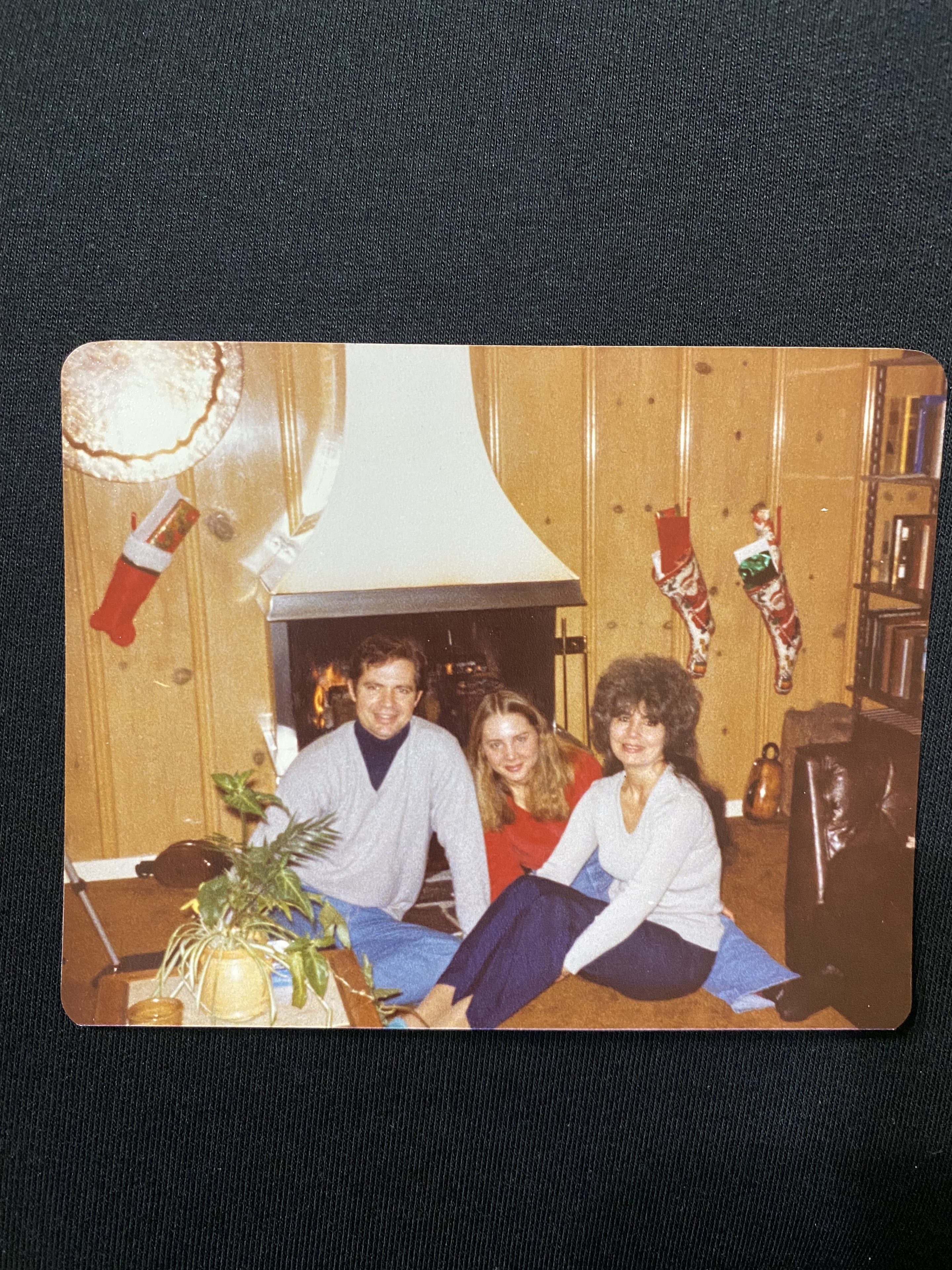 Three friends share cozy moments by the fireplace, surrounded by festive decor.
