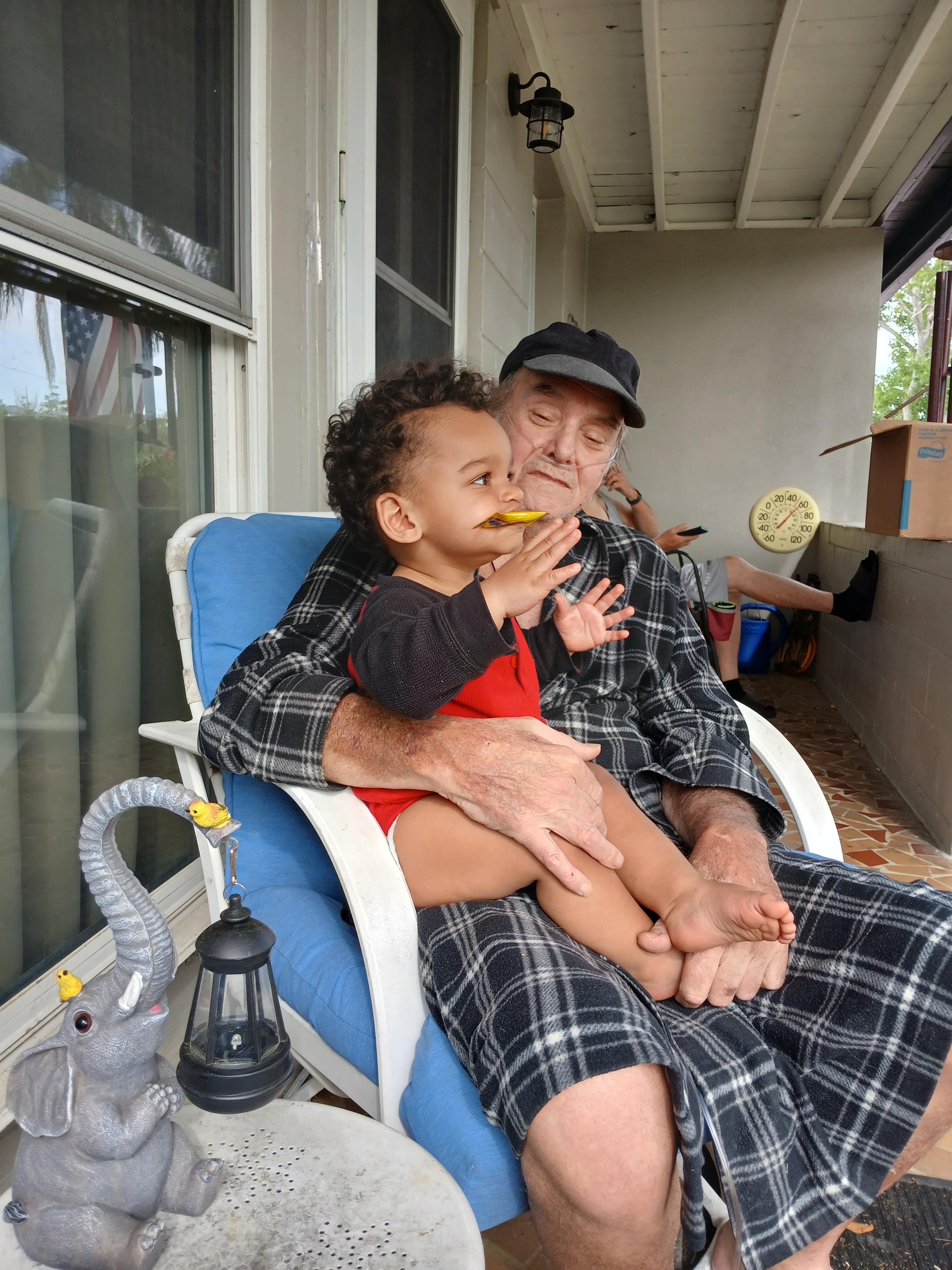 Grandfather and grandson share a joyful moment eating together on a cozy porch.
