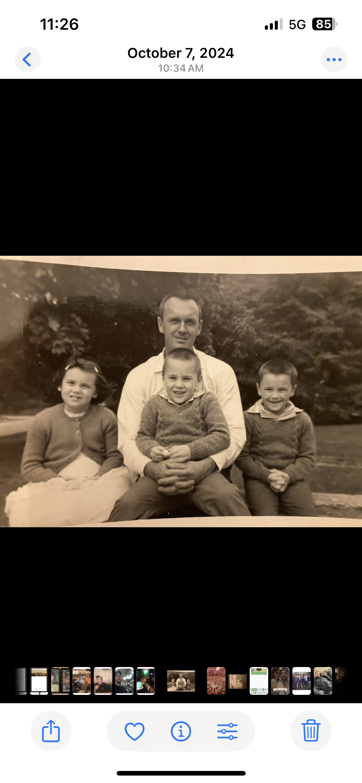 A nostalgic family gathering shows a man with three smiling children in a garden.
