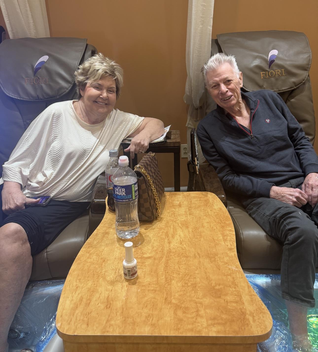 Friends relax in comfy chairs at a spa, laughing and enjoying pedicures together.
