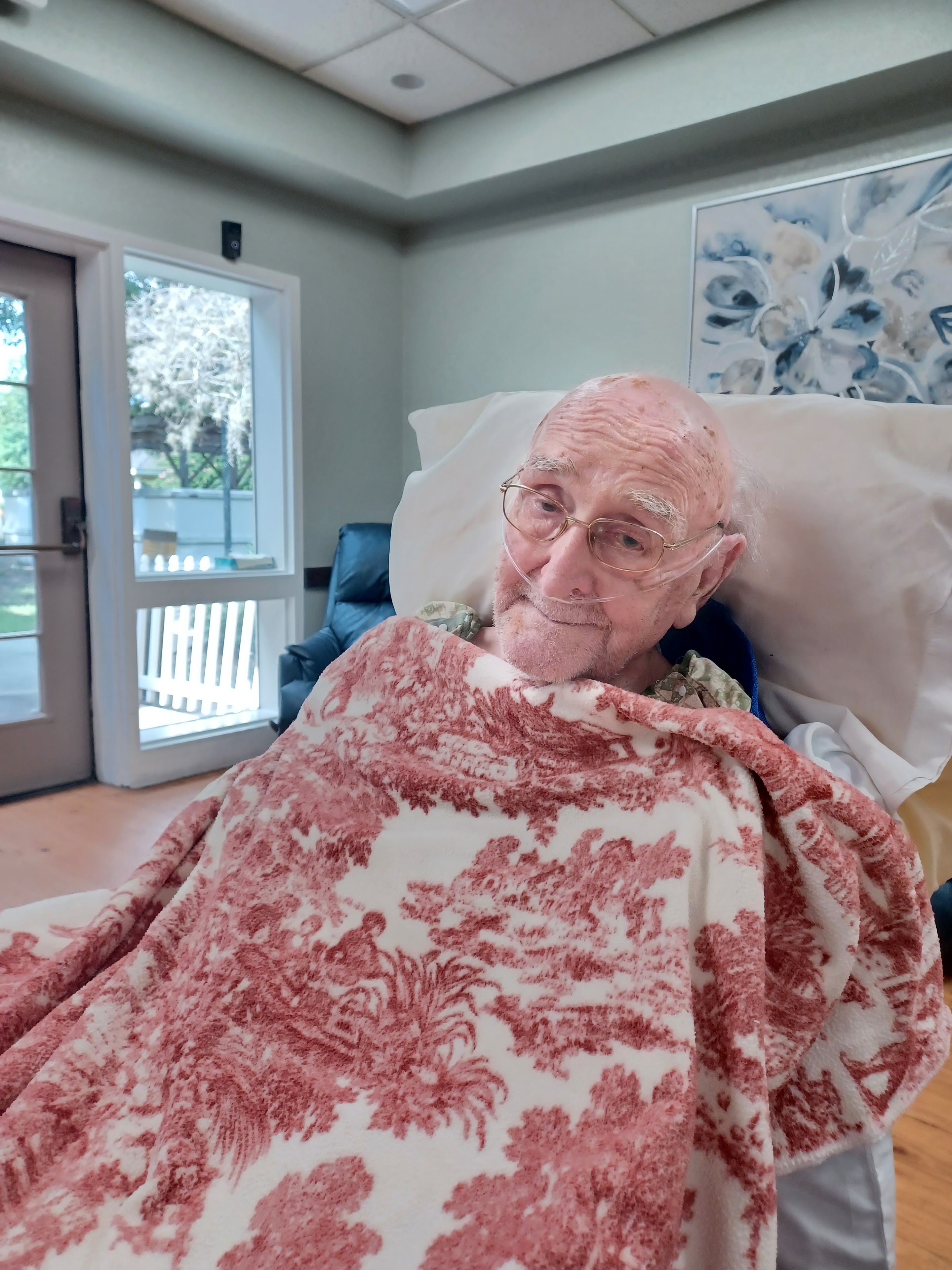 An elderly person relaxes in a nursing home, warmly dressed in a peaceful setting.