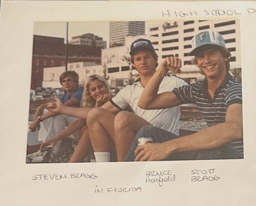 Four friends sit by the water in Florida, sharing smiles and drinks during a sunny day.