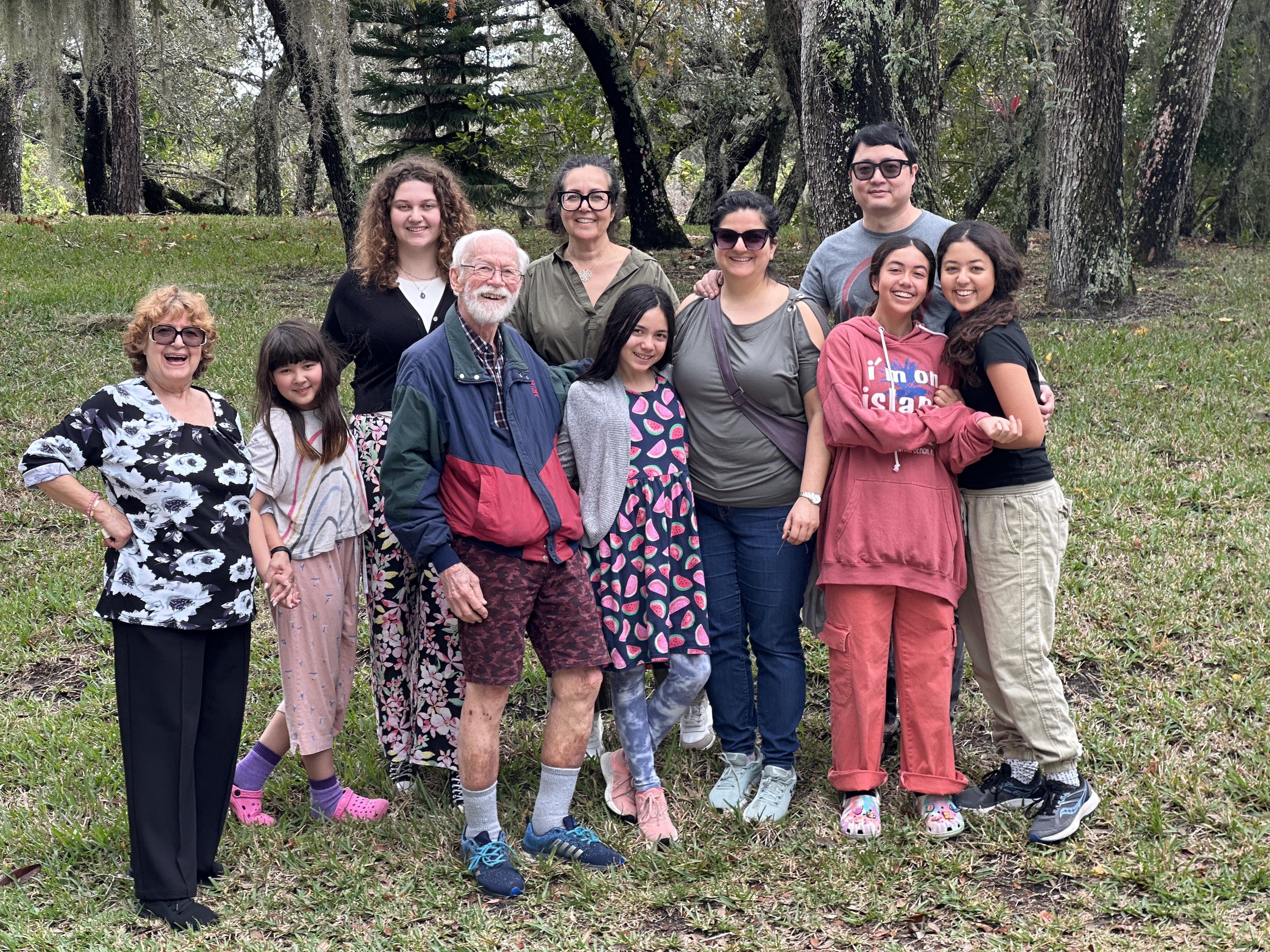 A group of diverse individuals poses together in a park, celebrating family closeness and joy.