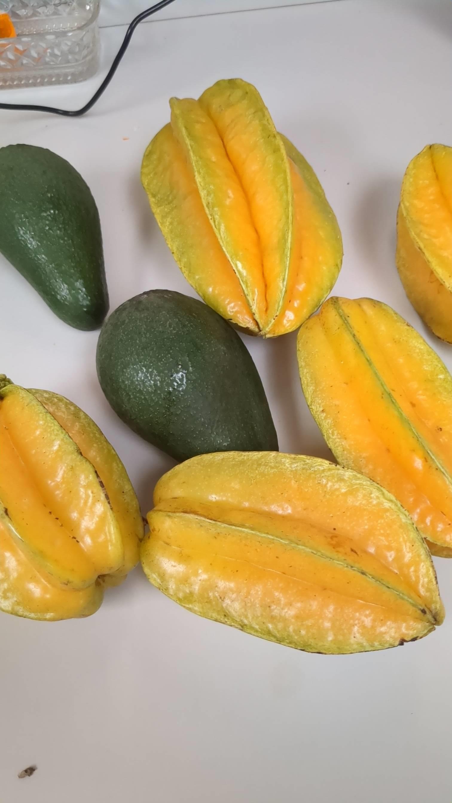 Fresh starfruits and avocados display their vibrant colors on a neutral background.