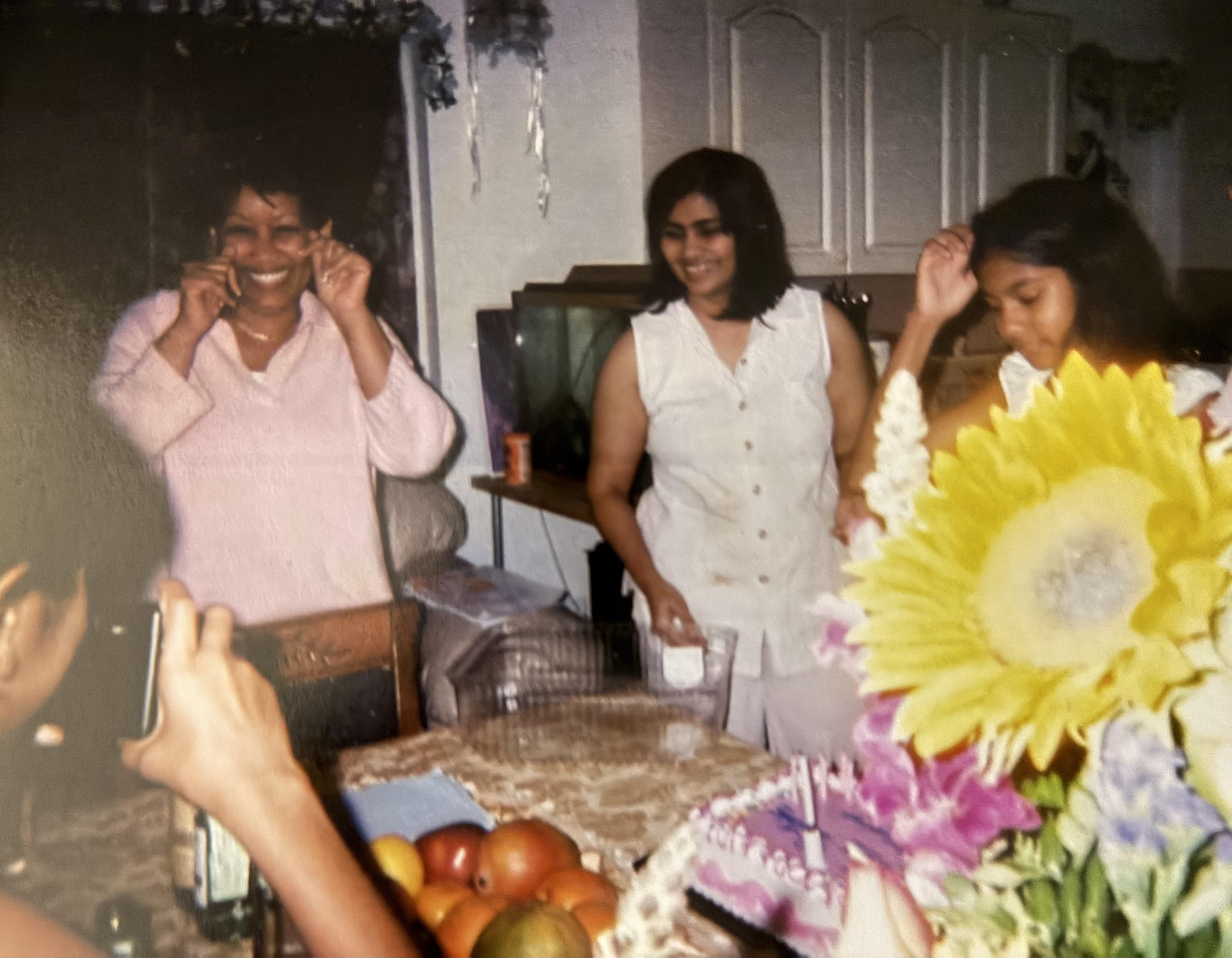 Three women are smiling and enjoying each other's company during a festive family gathering.