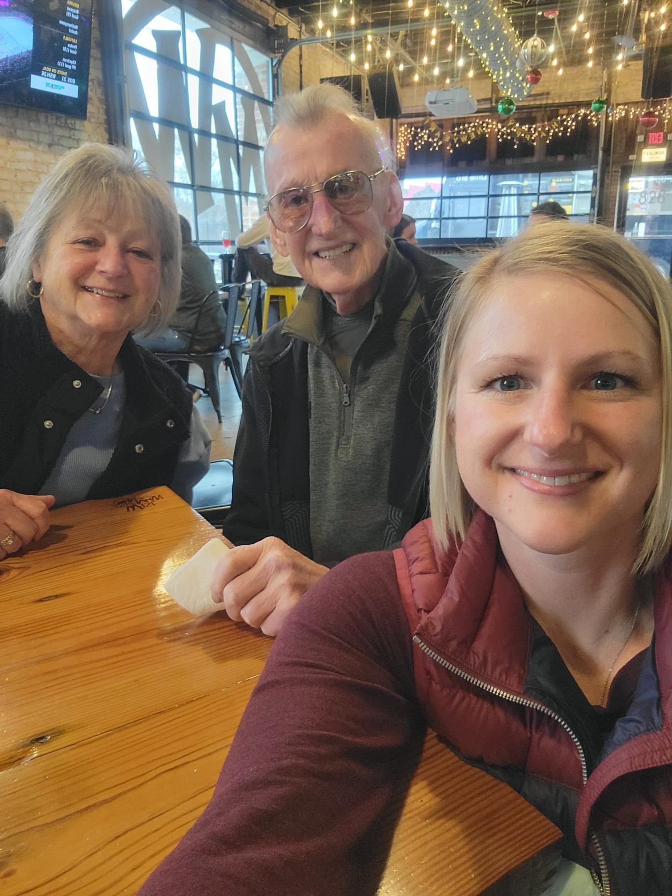 Three people enjoy their time together at a cafe, sharing laughter and good company.