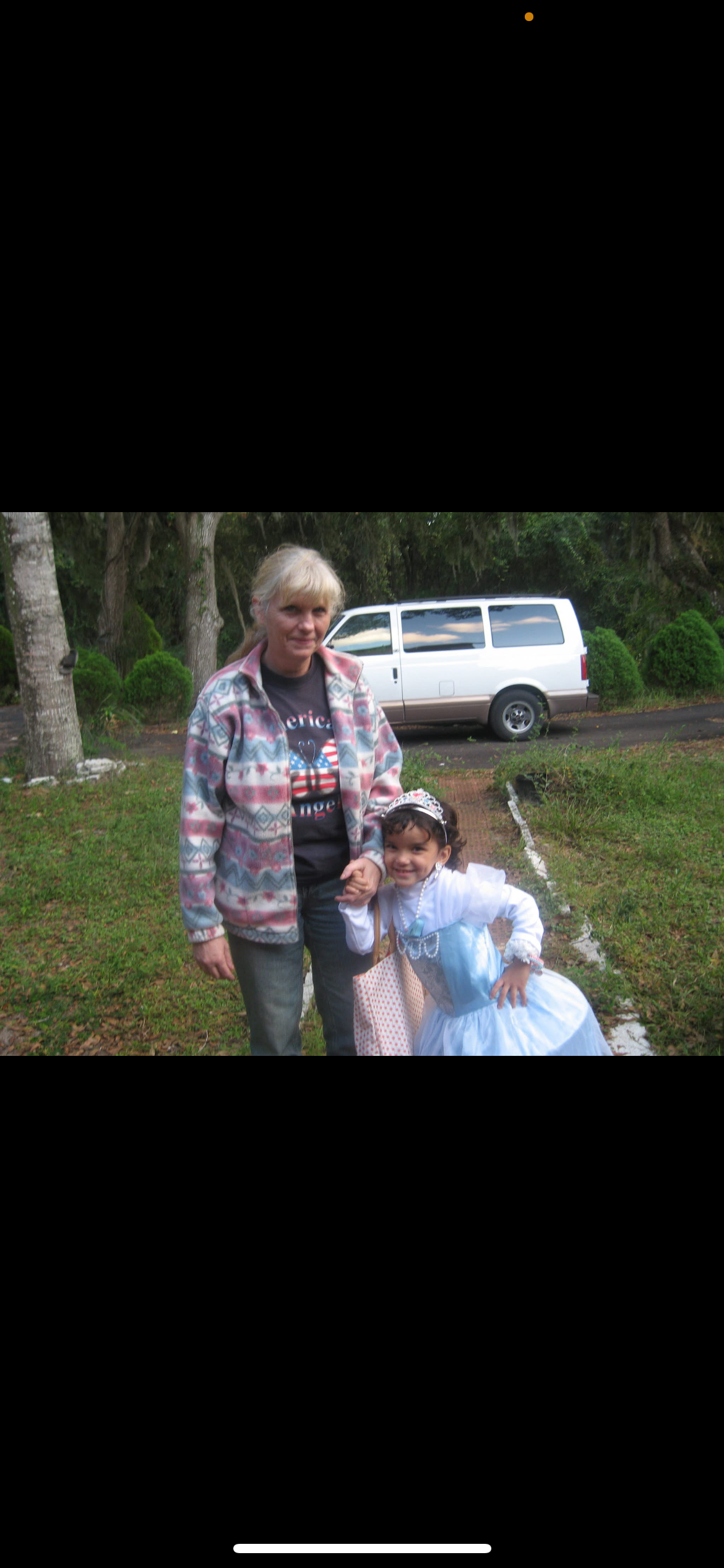 A child in a blue fairy tale costume and an adult are smiling together outdoors in a park.