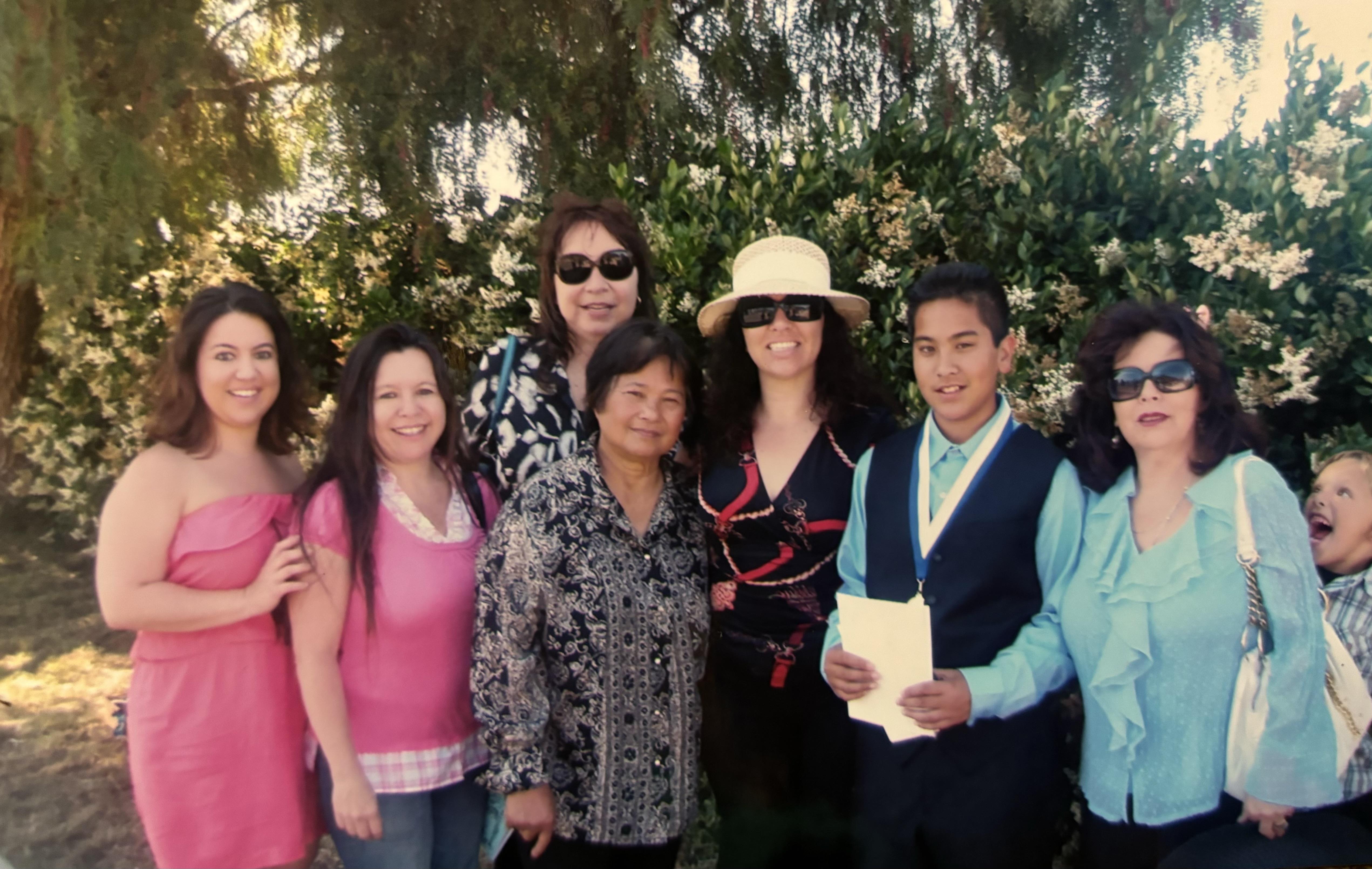 Family and friends joyfully celebrate a graduation together in a garden.