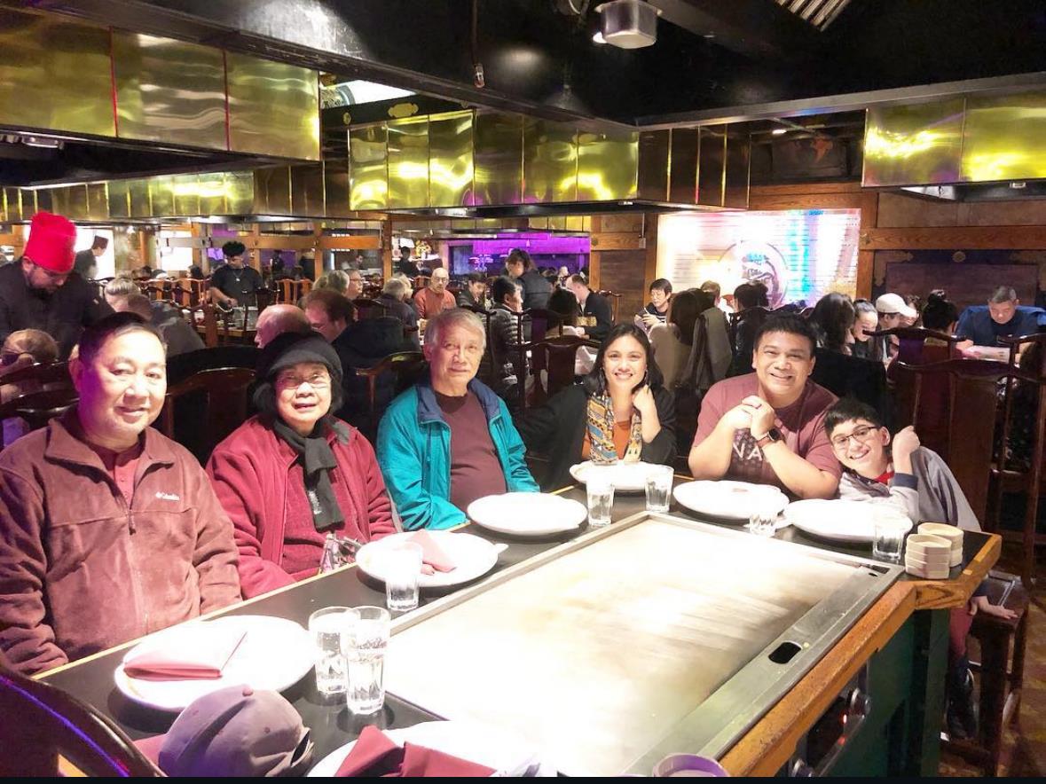 Group of friends enjoying a meal at a teppanyaki restaurant with lively chatter and delicious food.